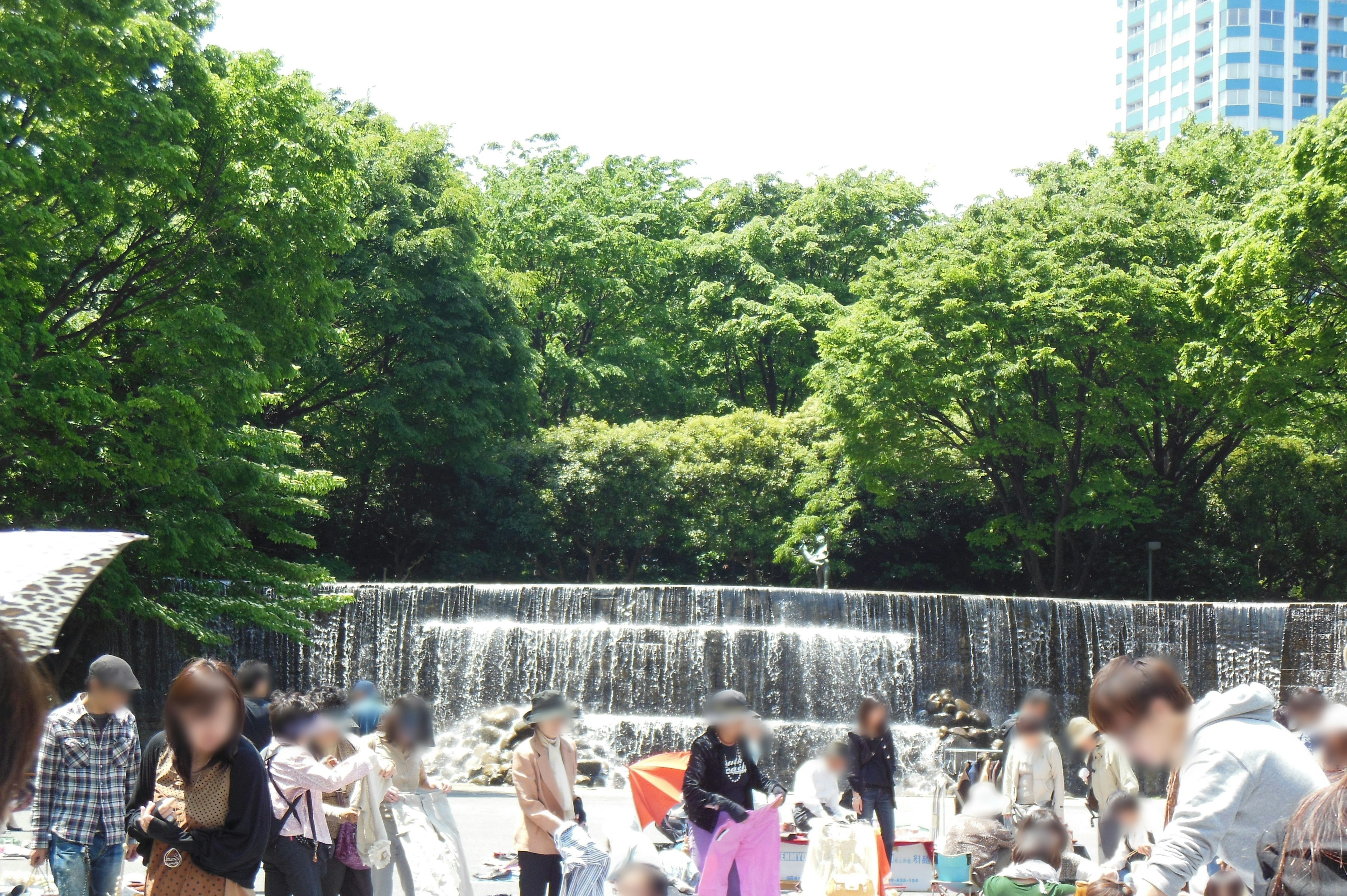 緑豊かな公園の滝の前で人々が集まり楽しんでいる