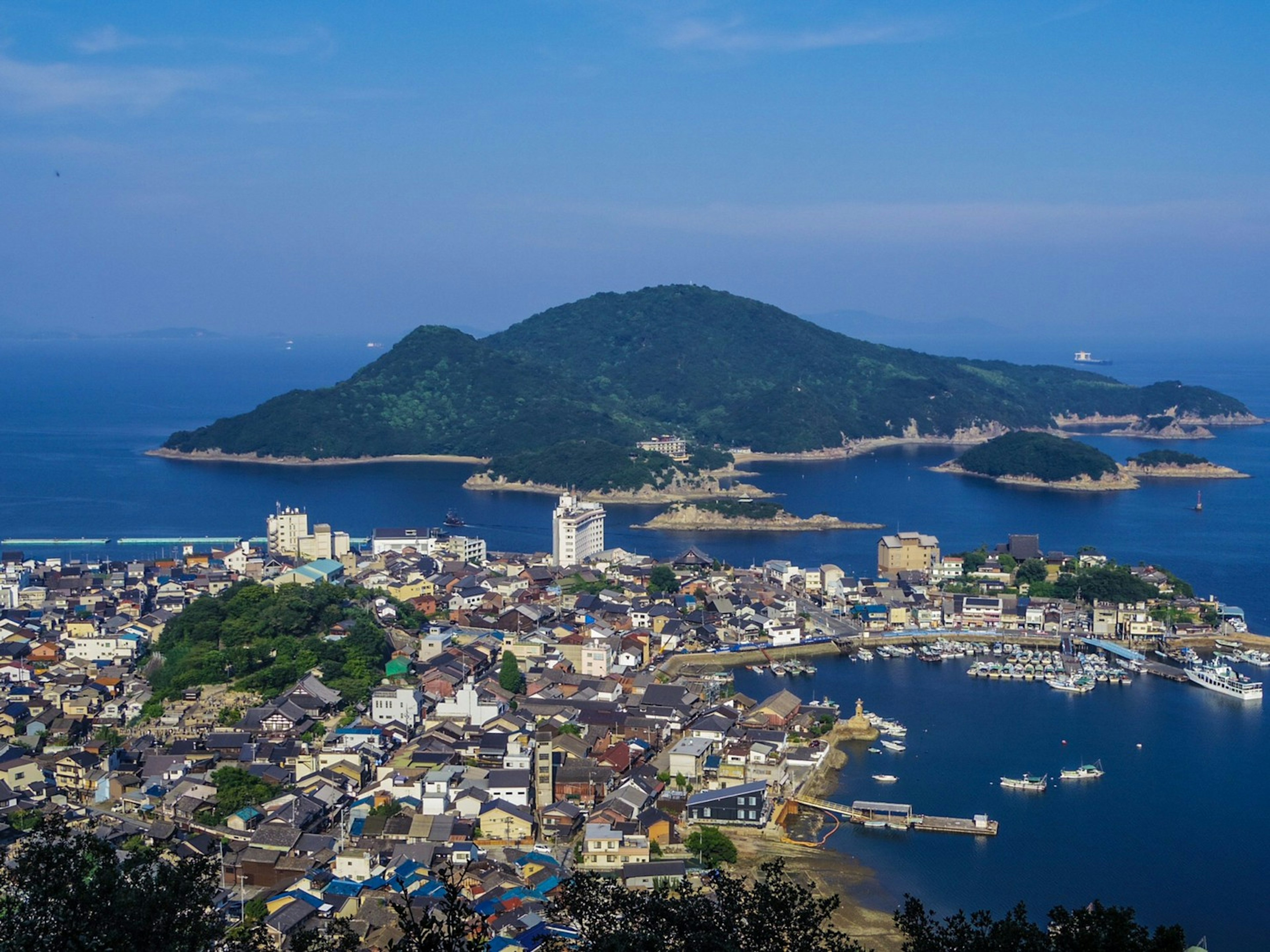 Vista panorámica de una ciudad costera rodeada de mar azul y una isla