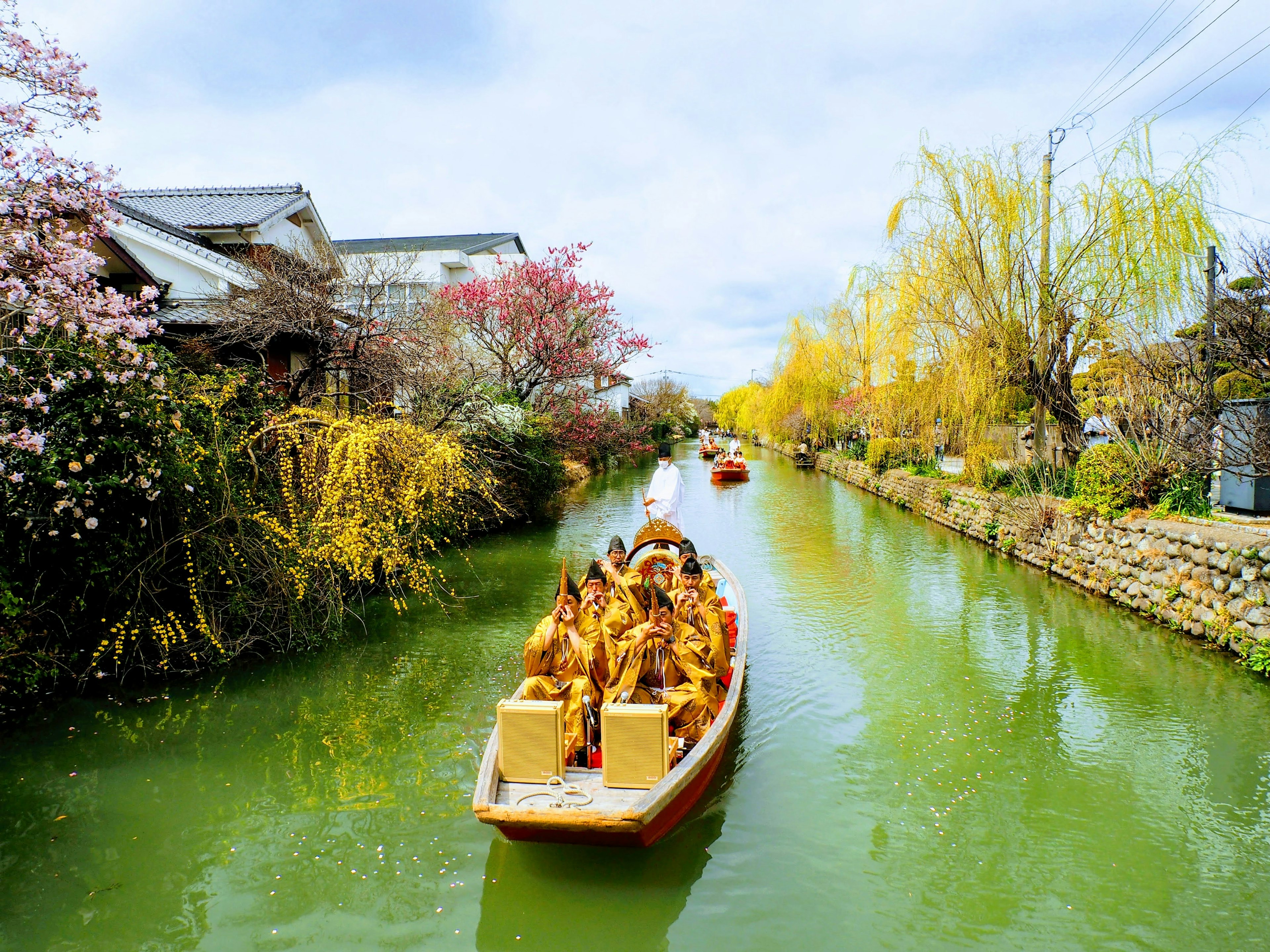 Boat navigating a green canal surrounded by colorful flowers