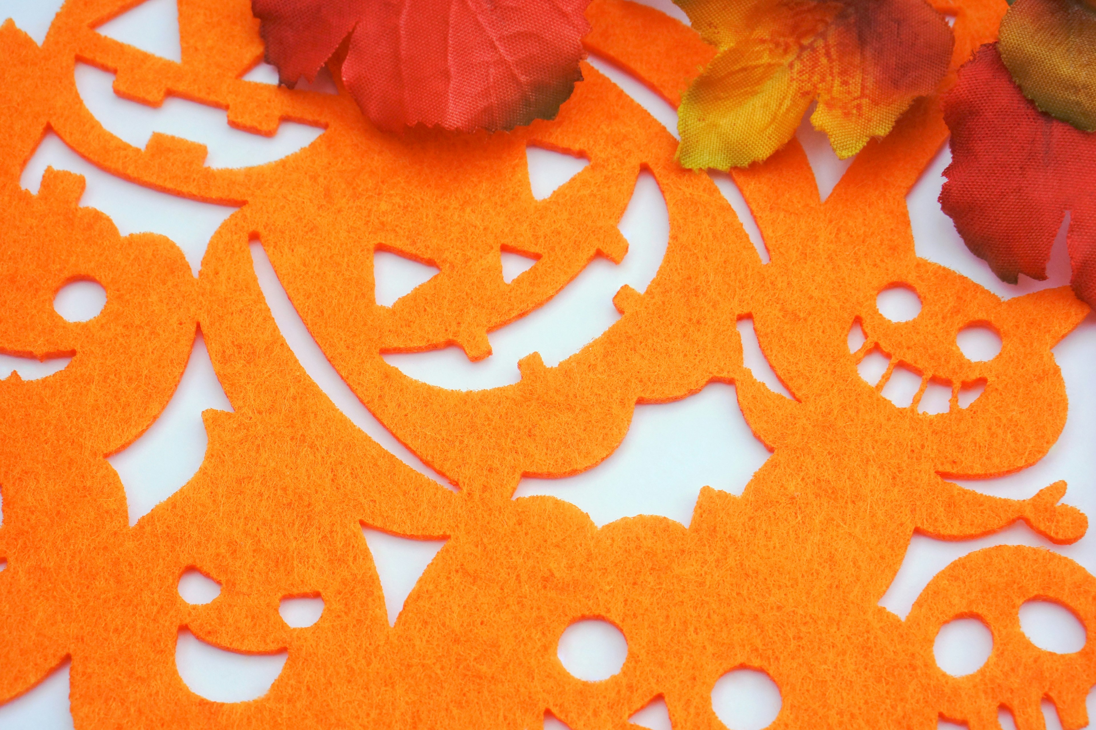 Décorations d'Halloween en feutre orange avec des visages souriants et effrayants et des pétales de fleurs