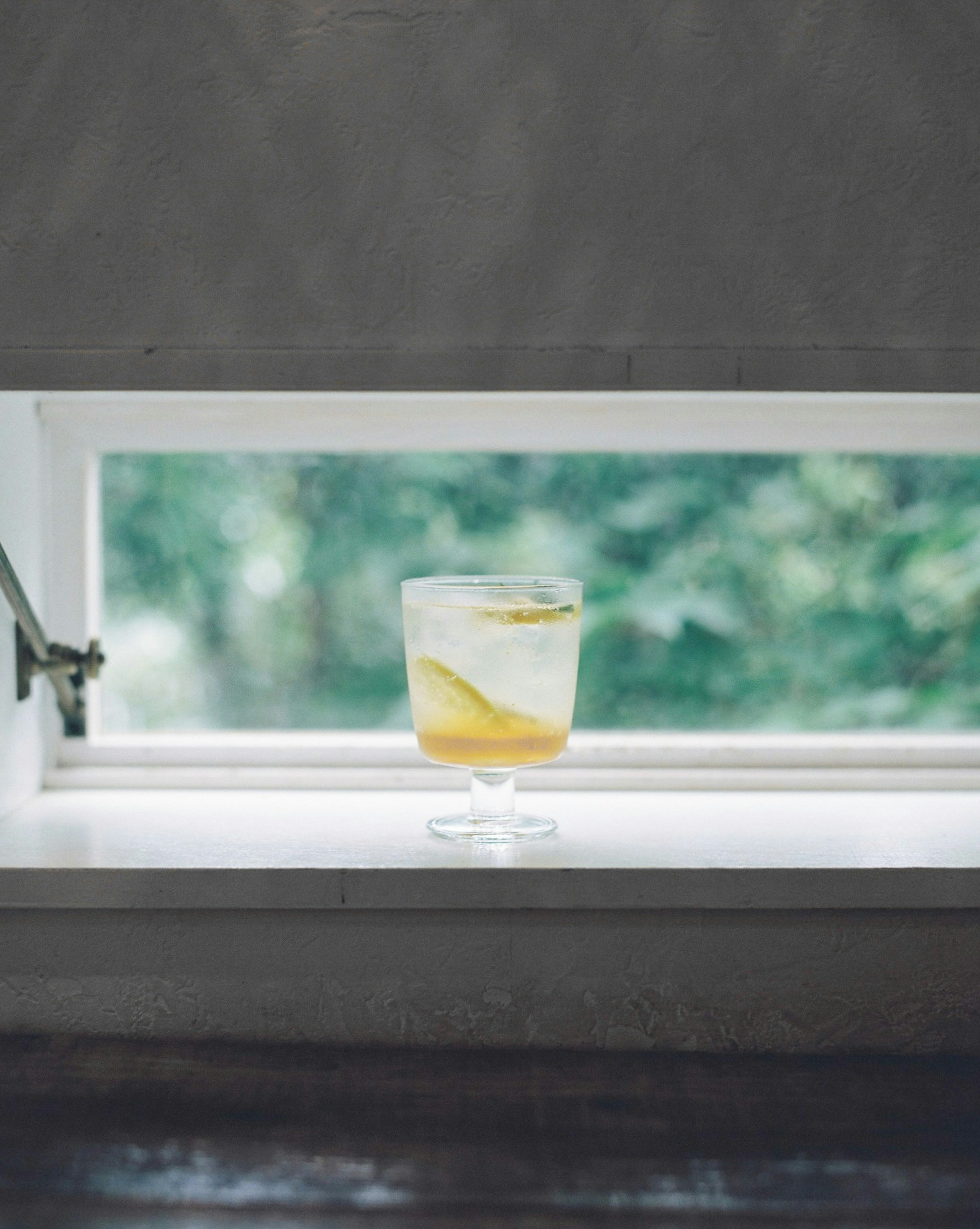 Cocktailglas mit Zitronenscheibe auf einer Fensterbank