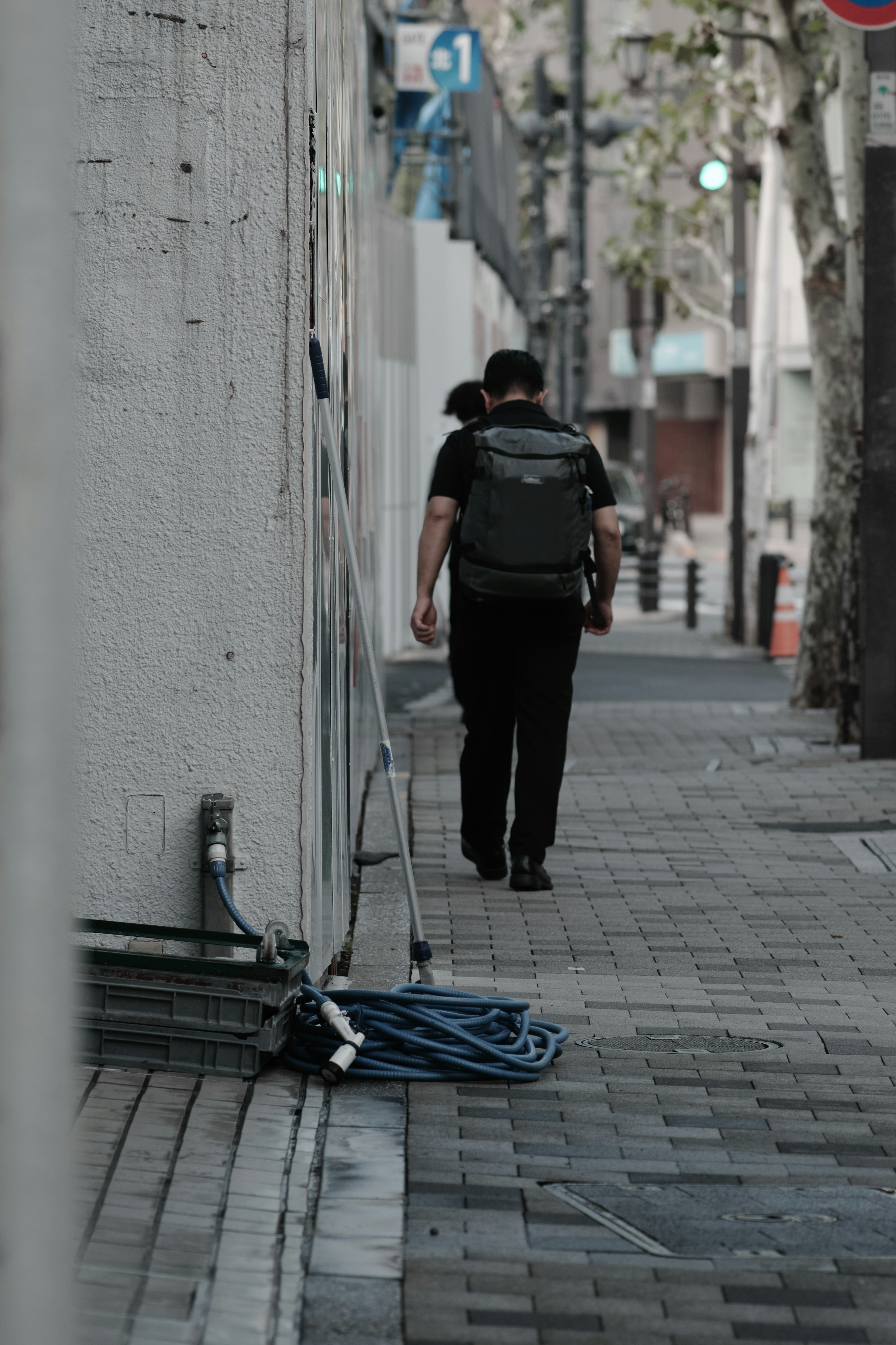 A man walking down an urban street carrying a backpack