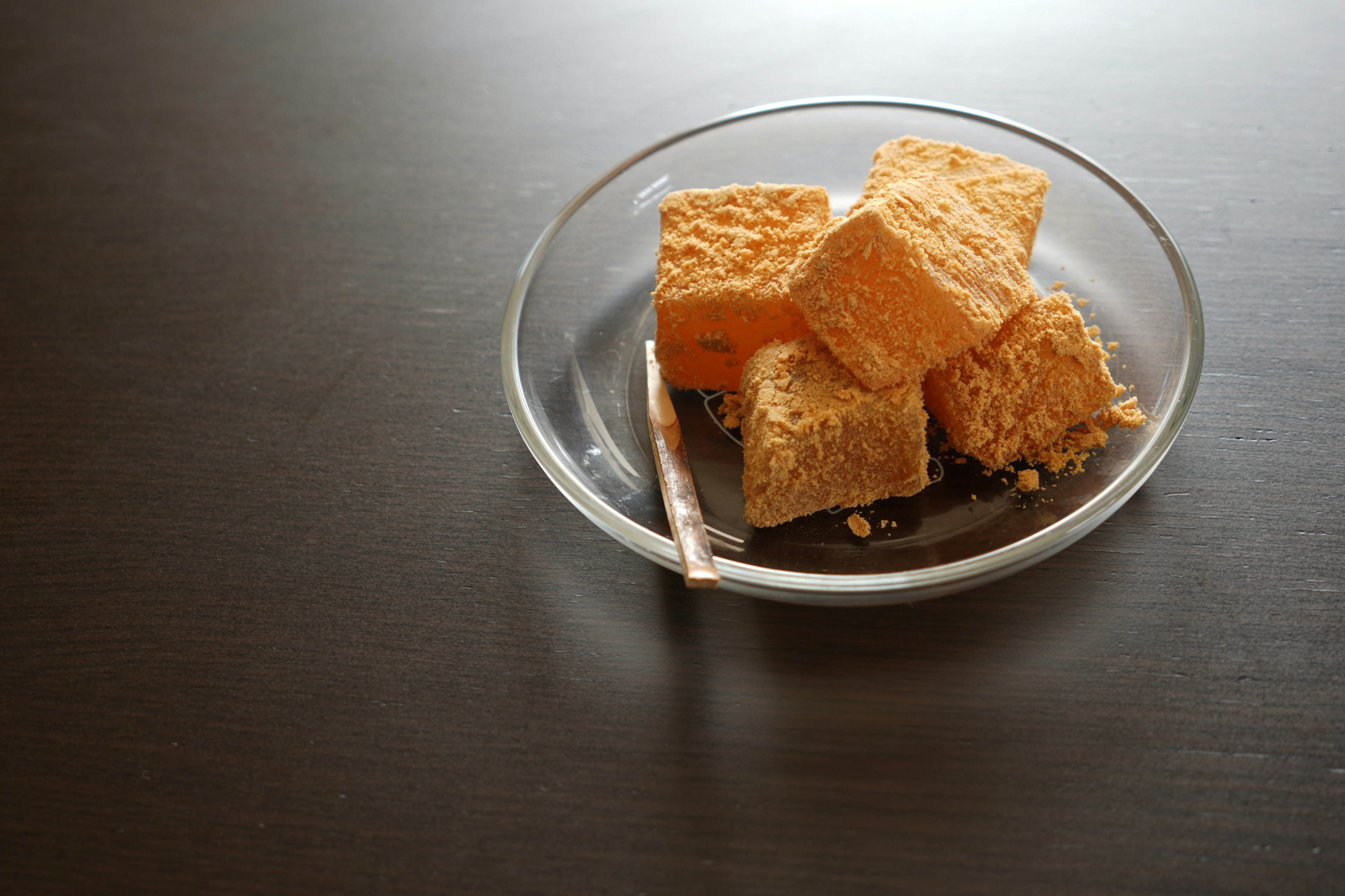 Dulces naranjas cuadrados en un plato transparente