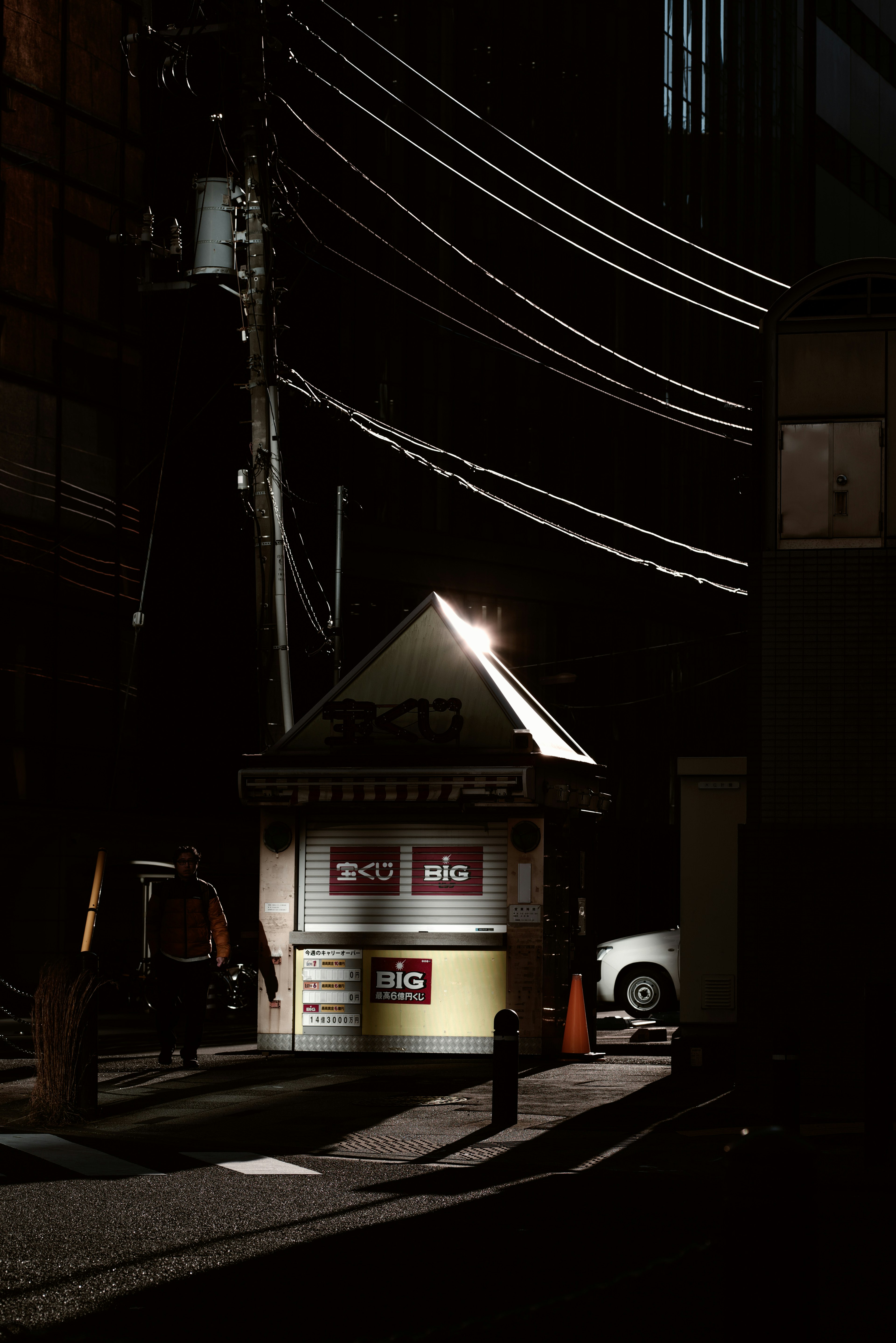 Cabine illuminée dans une ruelle sombre avec des lignes électriques