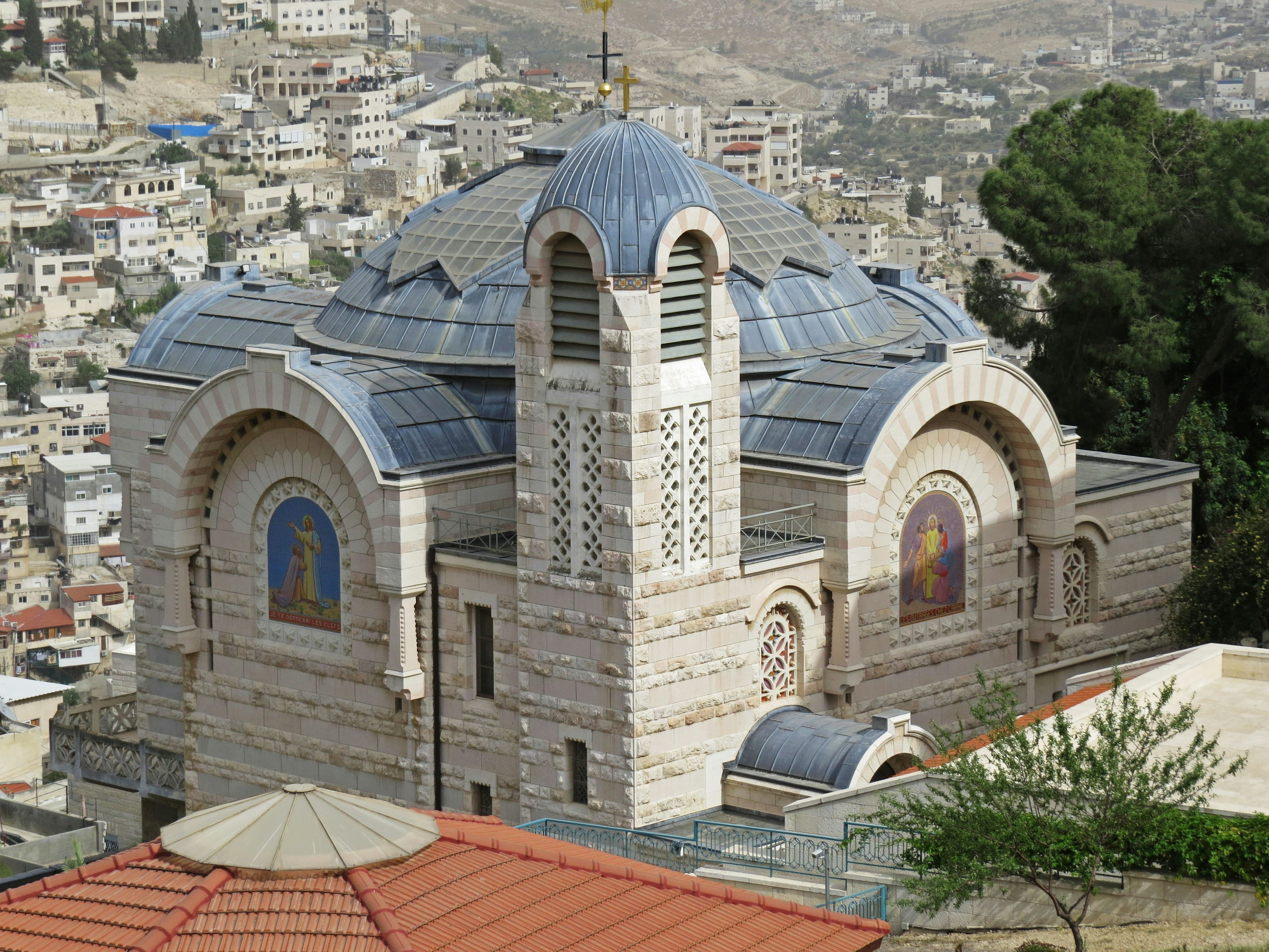 A beautiful church with a domed roof located on a hillside surrounded by buildings