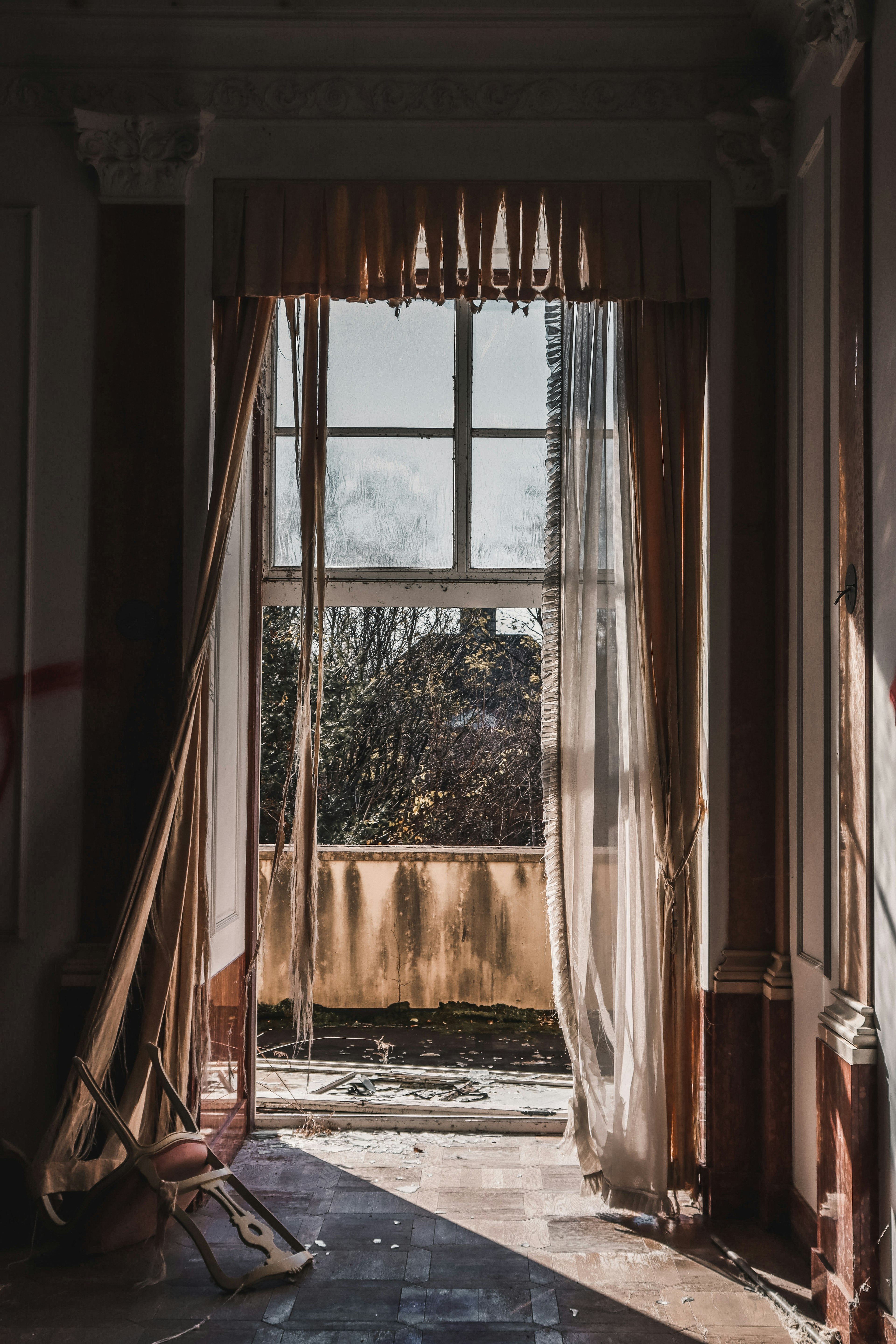 An old room with sunlight streaming through a window and flowing curtains