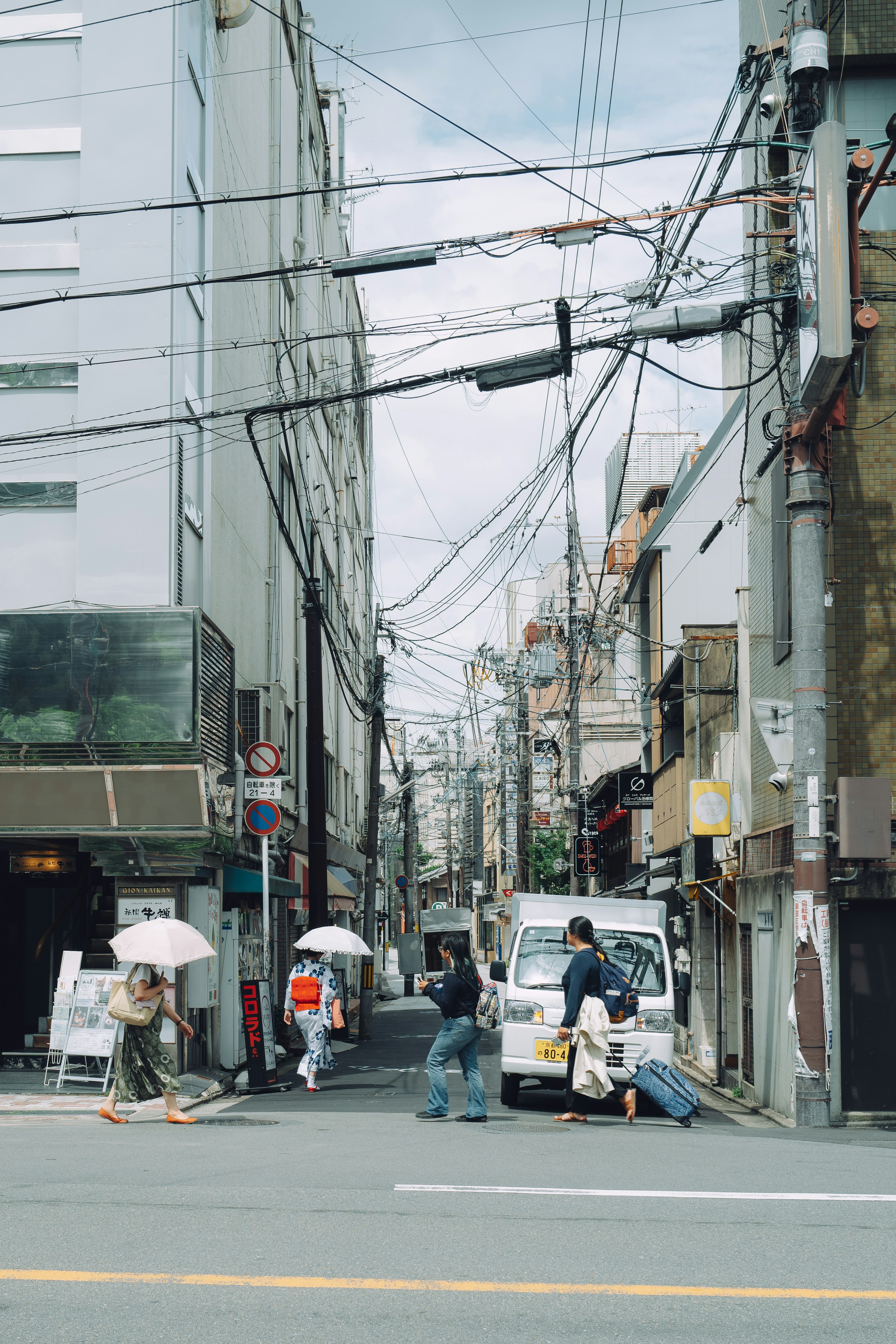 街の風景に人々が歩いている様子と傘を持つ人