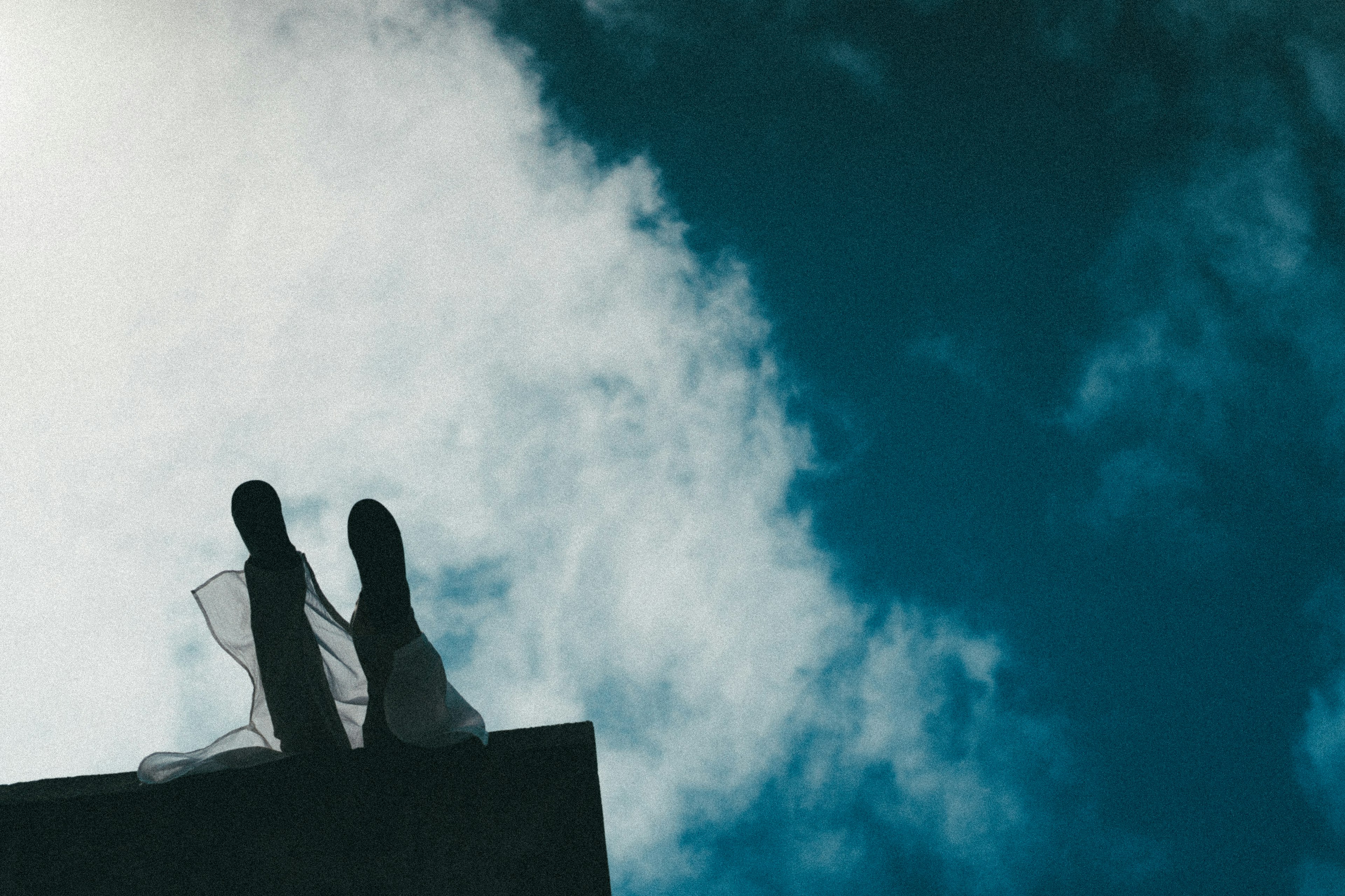 Feet in a wedding dress against a blue sky