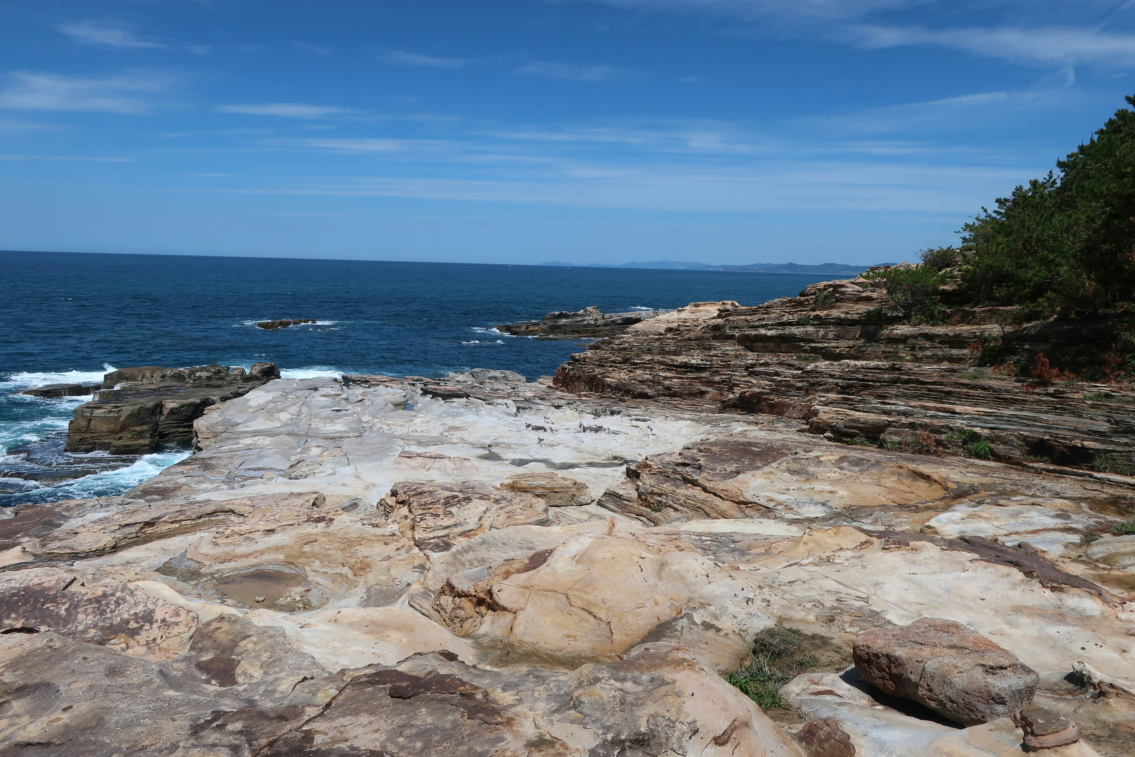 Pemandangan pesisir dengan batuan laut dan langit biru