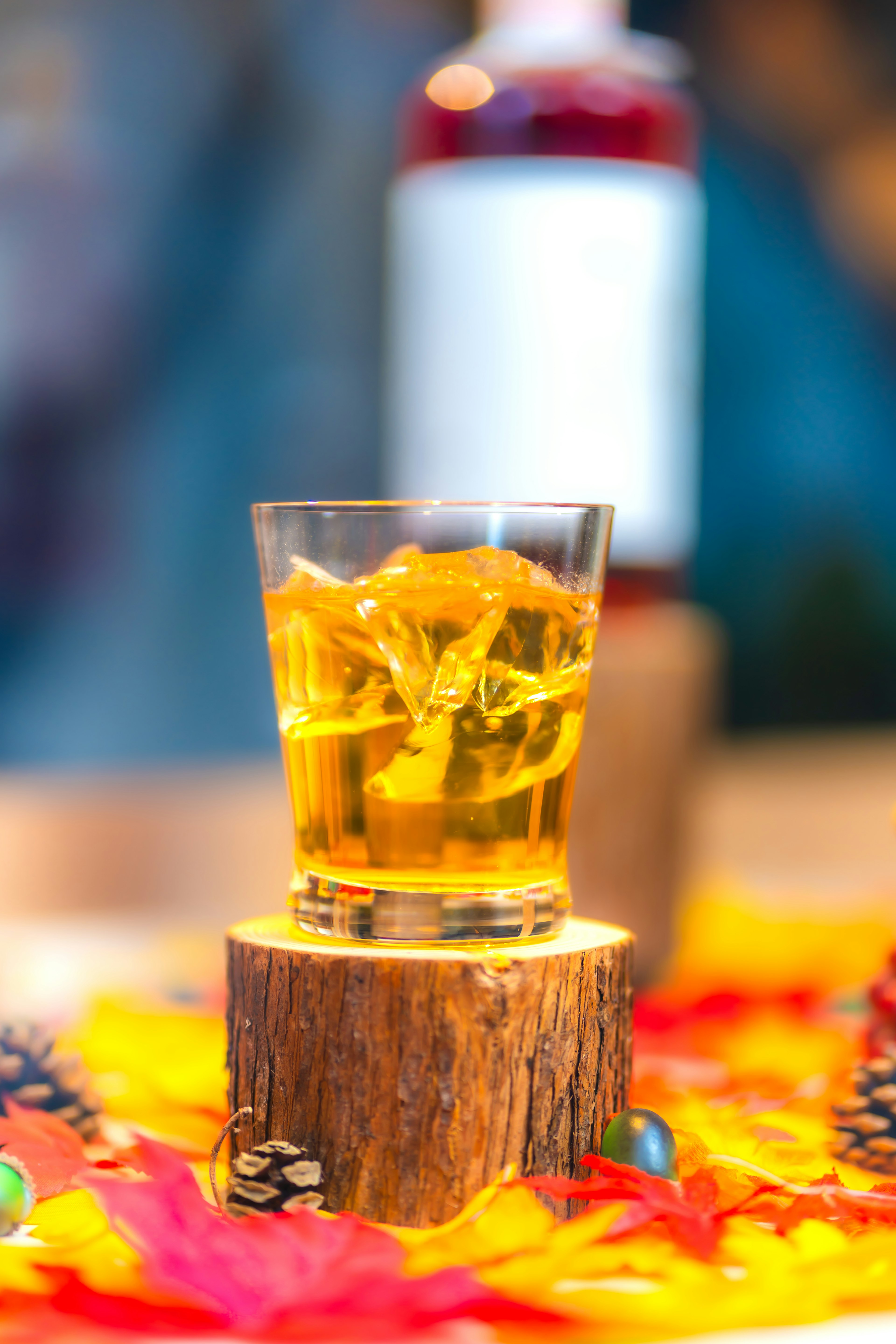 Glas mit Eistee auf einem Holzständer mit einer Flasche im Hintergrund