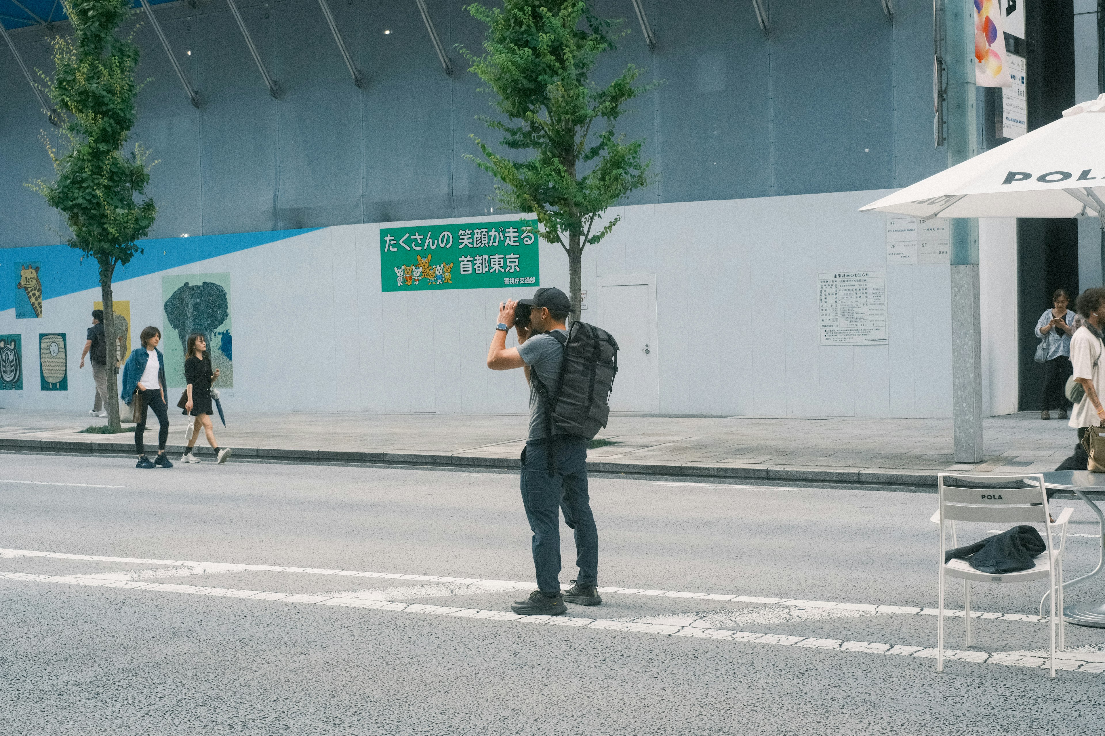 街角でカメラを持つ男性と通行人がいる風景