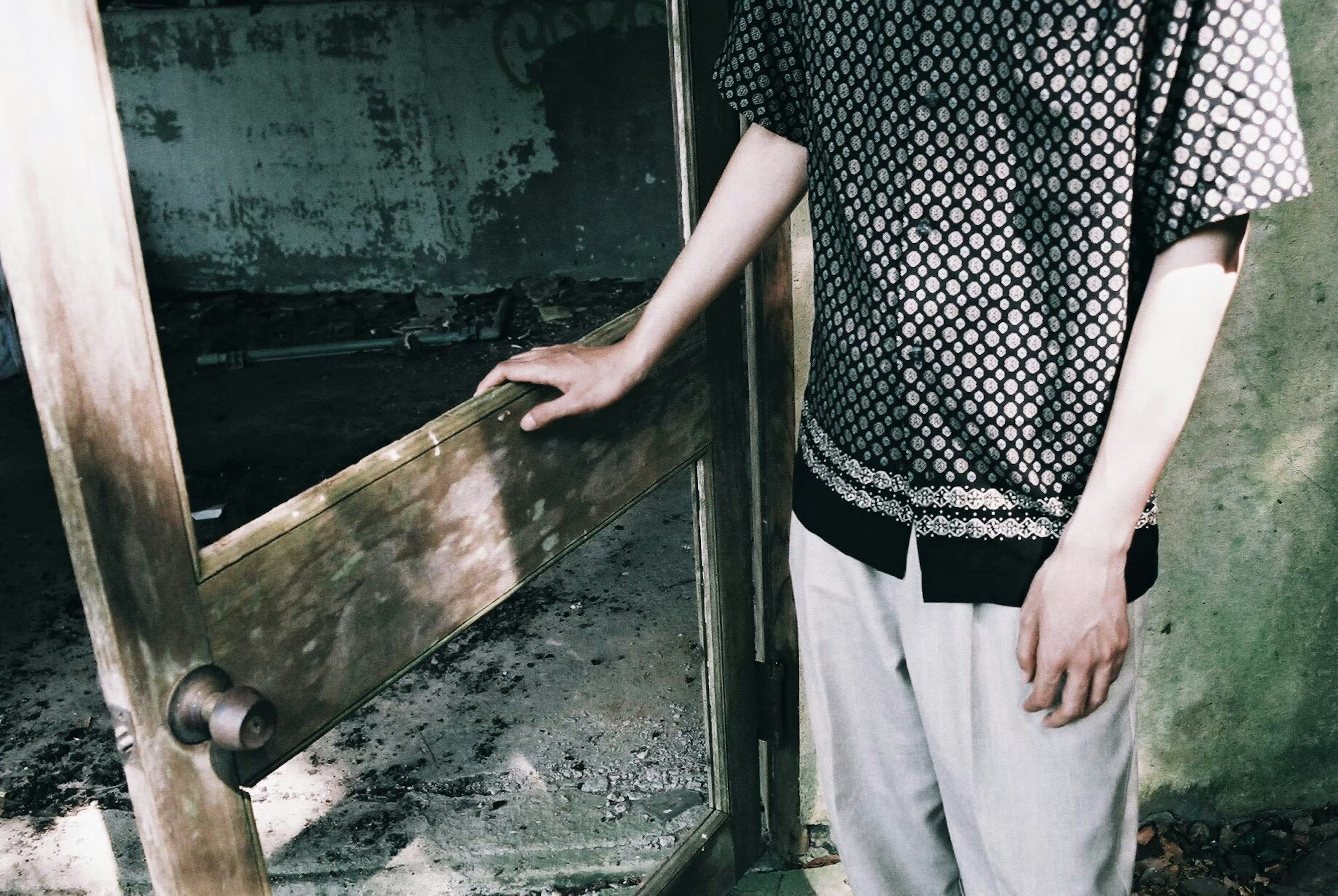 A person in an old building holding a broken door