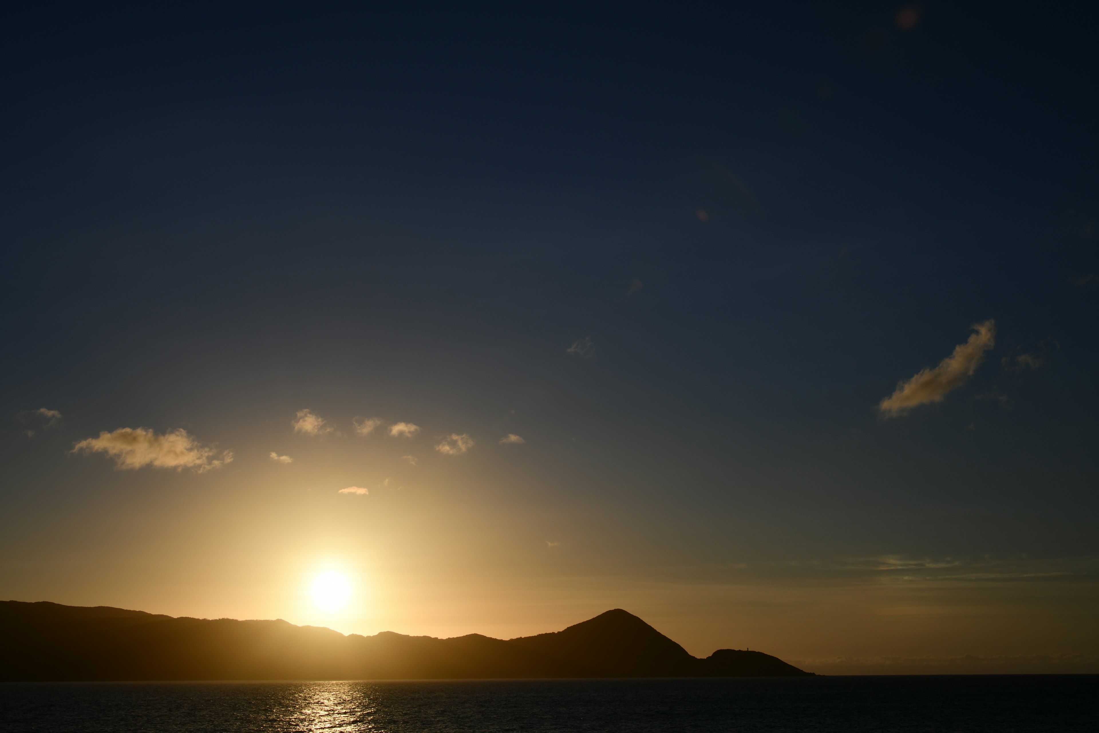 Tramonto sull'oceano con silhouette di montagne