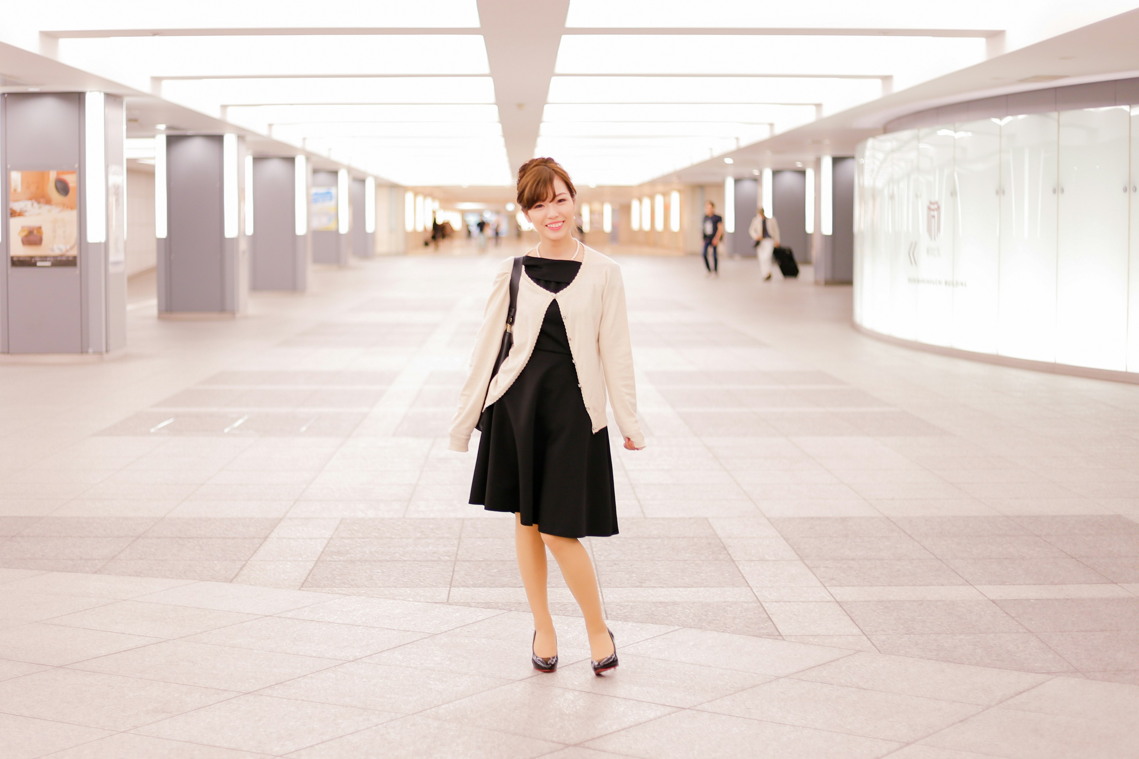 Femme en robe noire et veste blanche dans un espace moderne