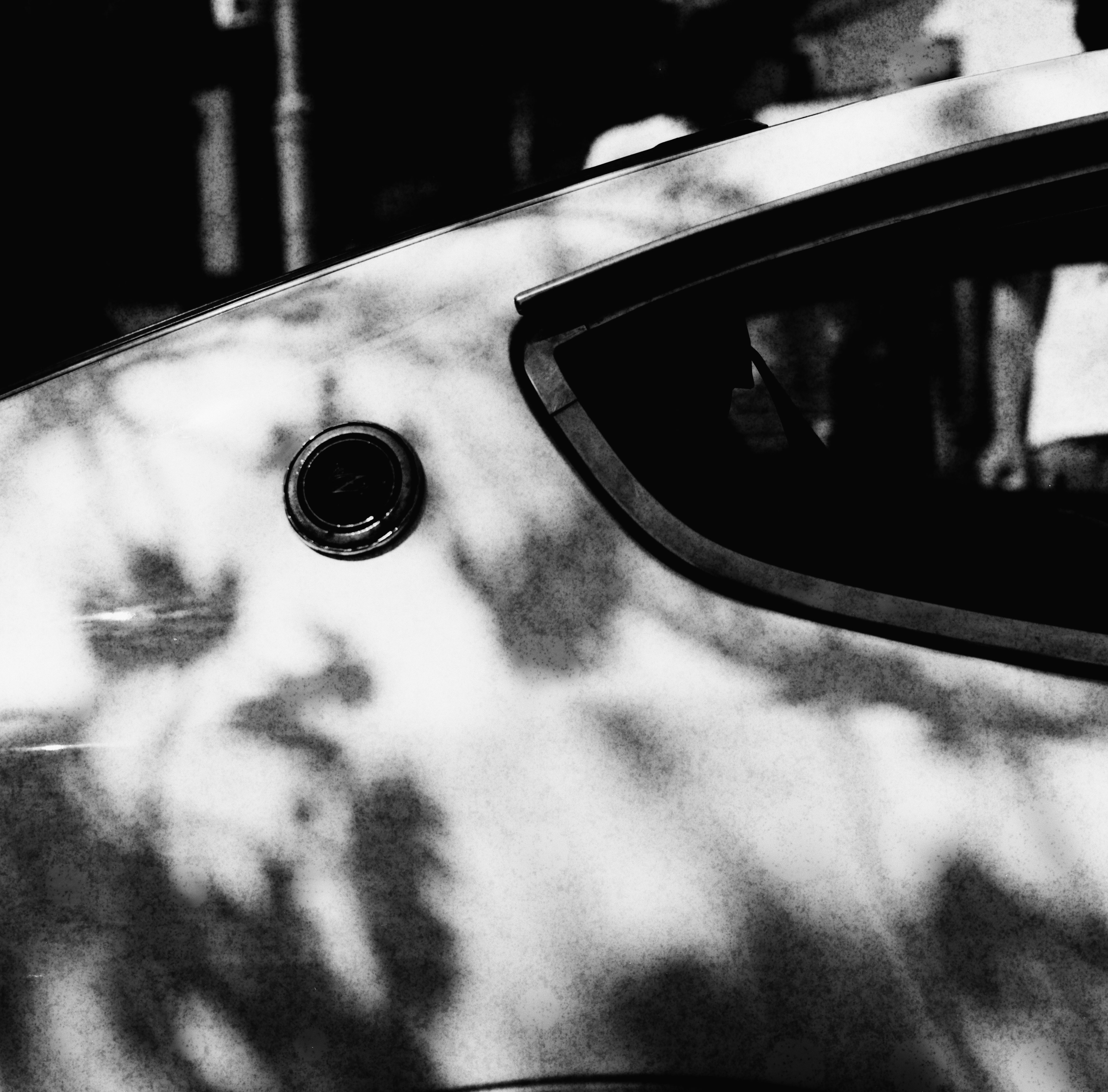 Black and white image of a car side with shadows and reflections