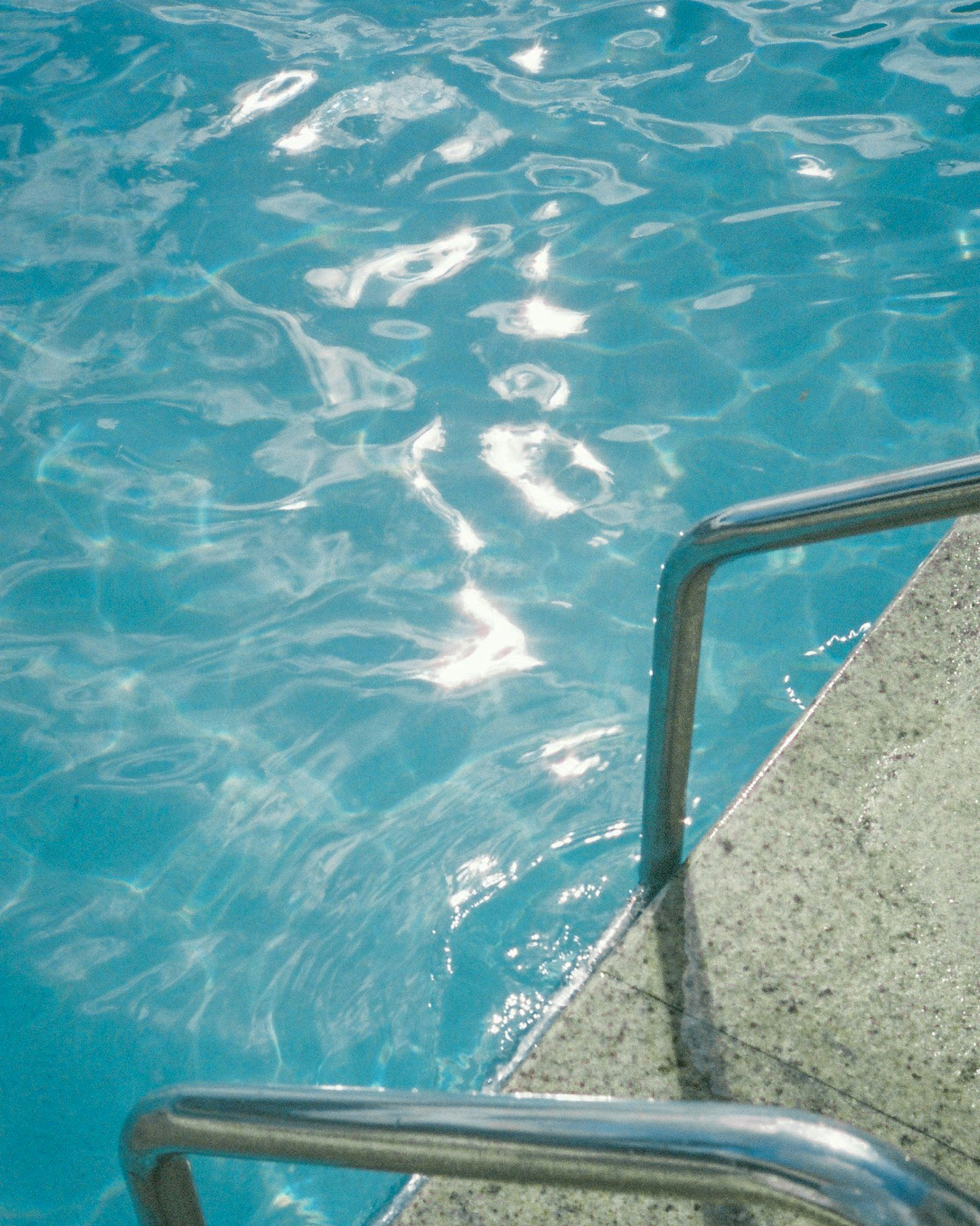 Superficie de agua de piscina azul con barandilla de acero inoxidable