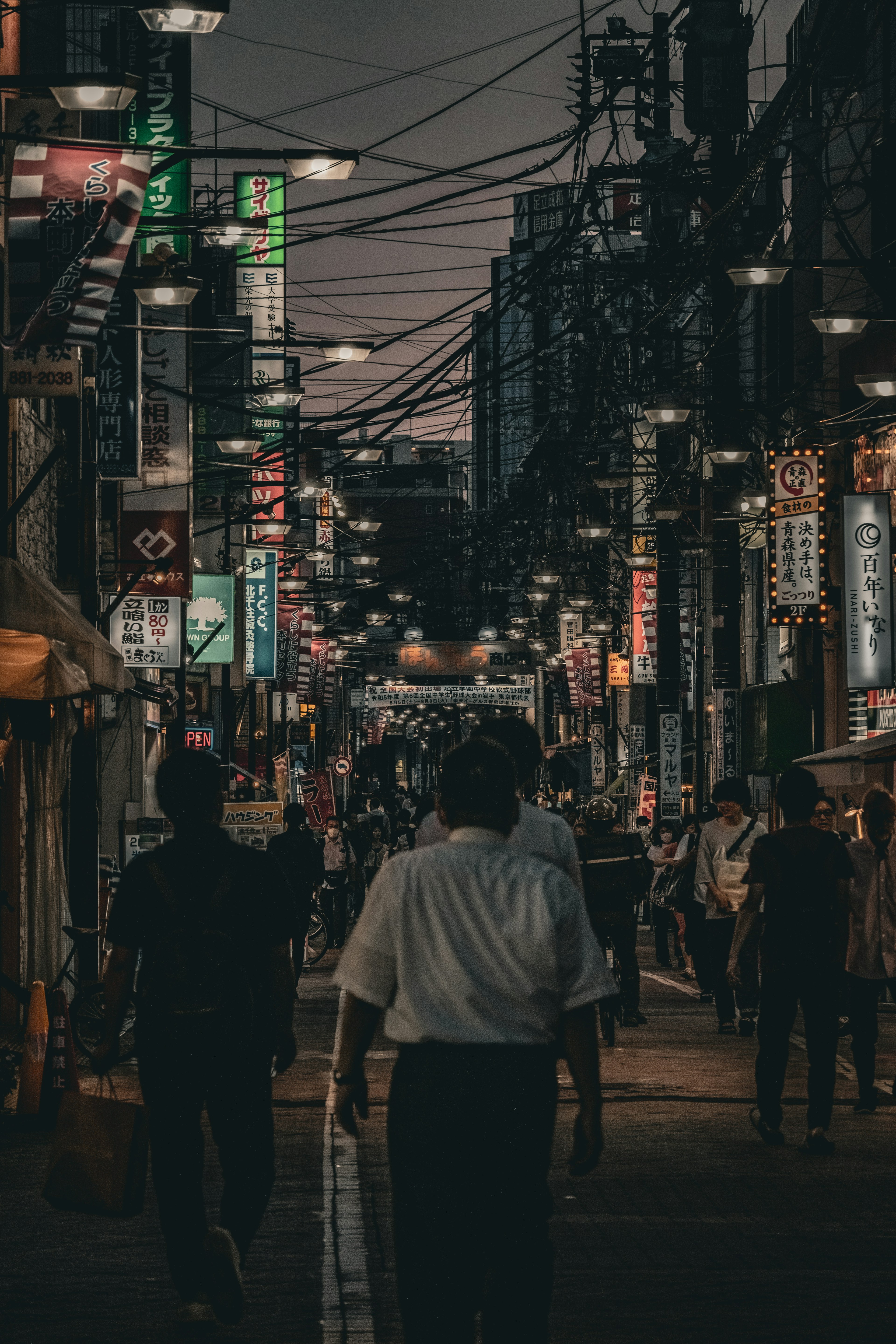 Kerumunan berjalan di jalan yang ramai dengan lampu neon di malam hari