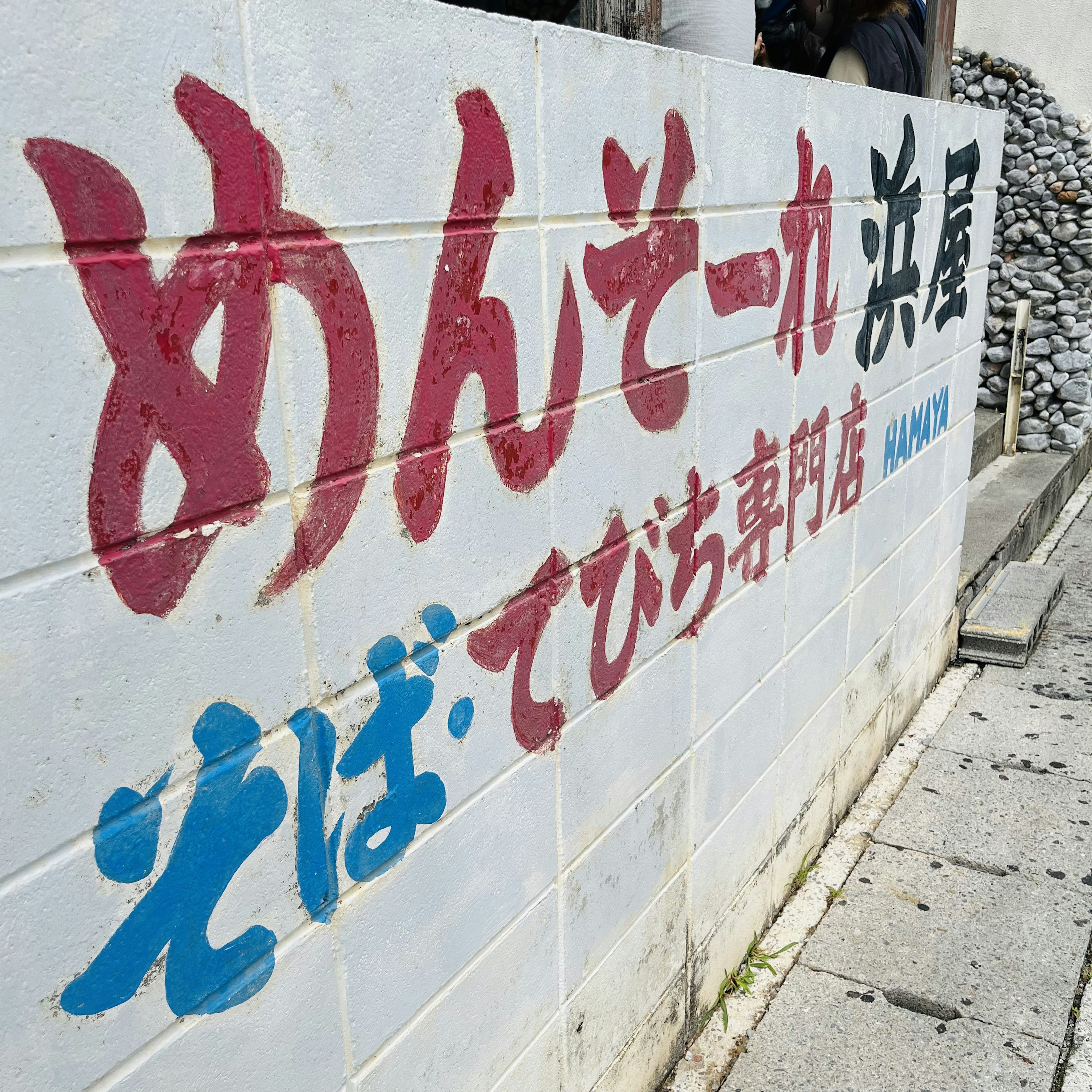 Una pared blanca con texto rojo y azul que muestra el nombre de la tienda y el menú