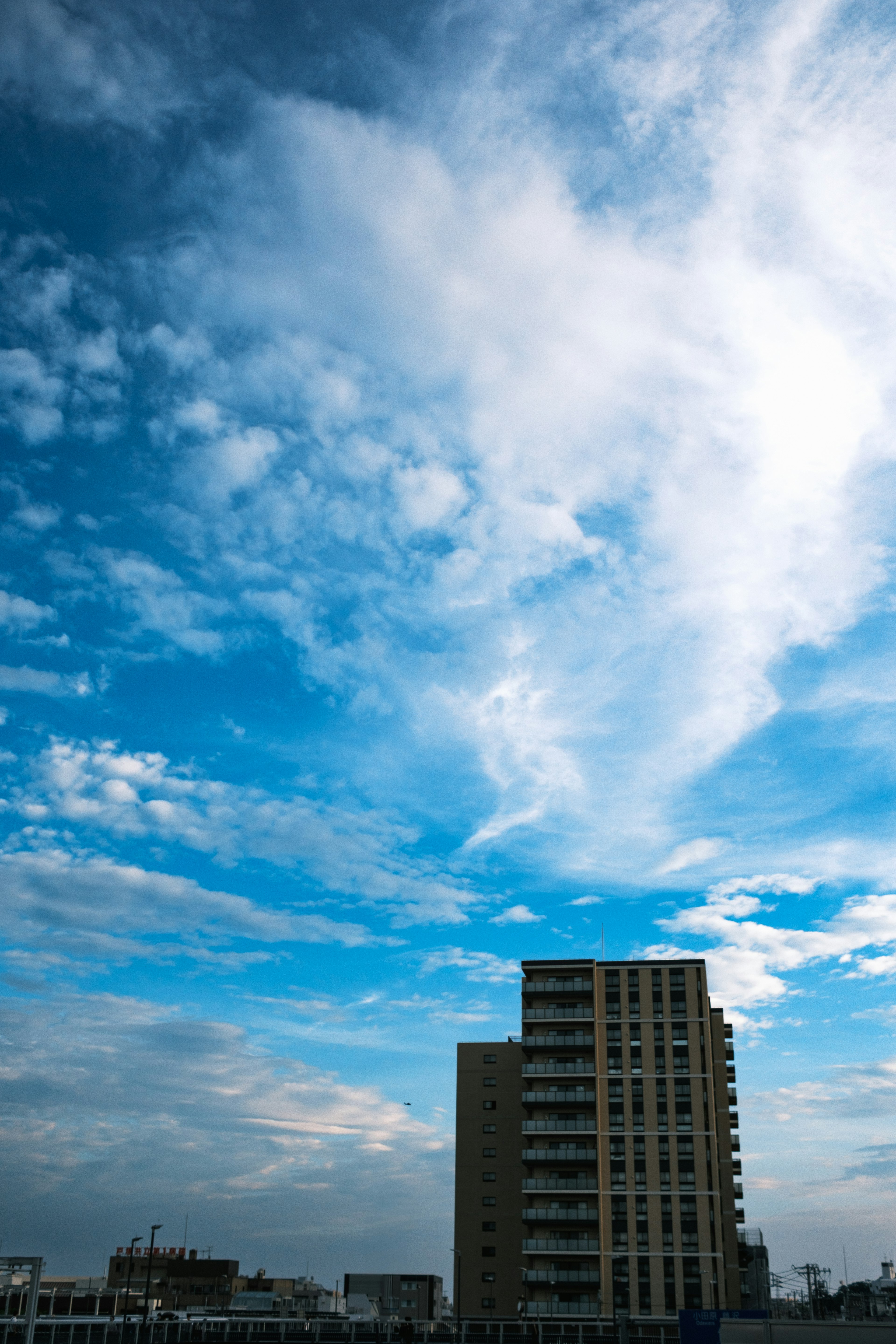 Un bâtiment haut sous un ciel bleu avec des nuages éparpillés