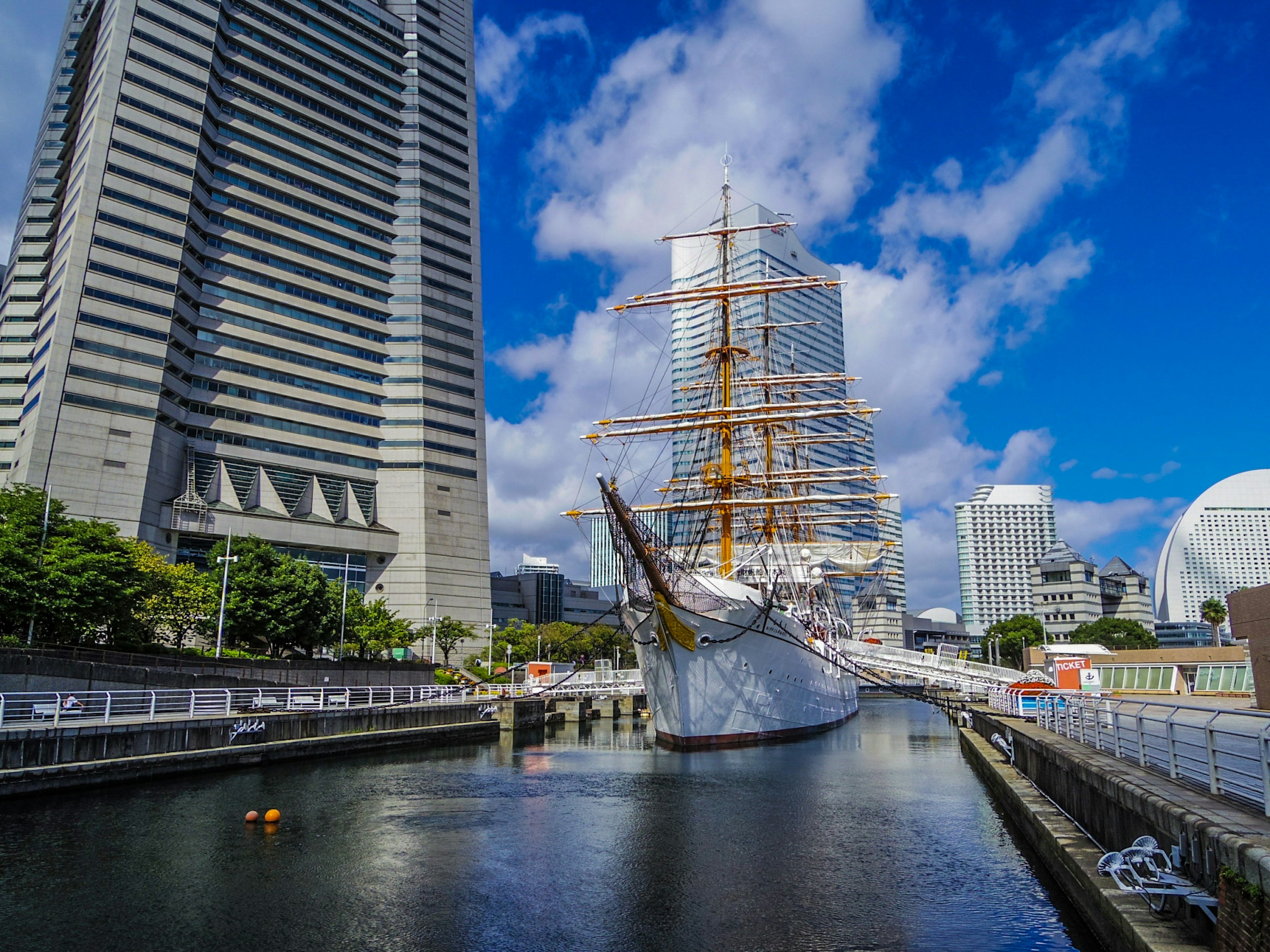 Une vue d'un navire à voiles amarré dans le port de Yokohama avec des gratte-ciel en arrière-plan