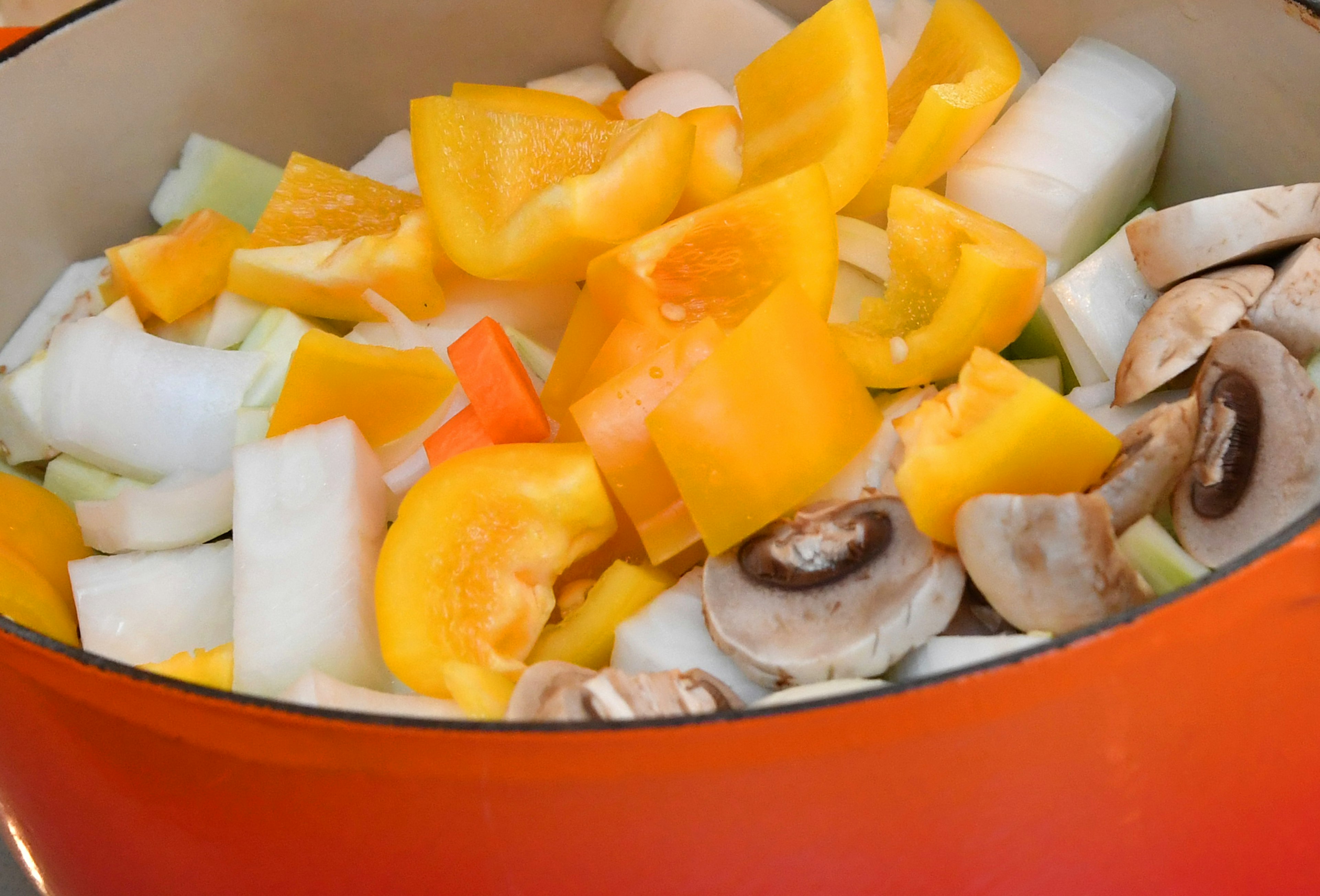 Colorful vegetables in a pot including bell peppers and mushrooms