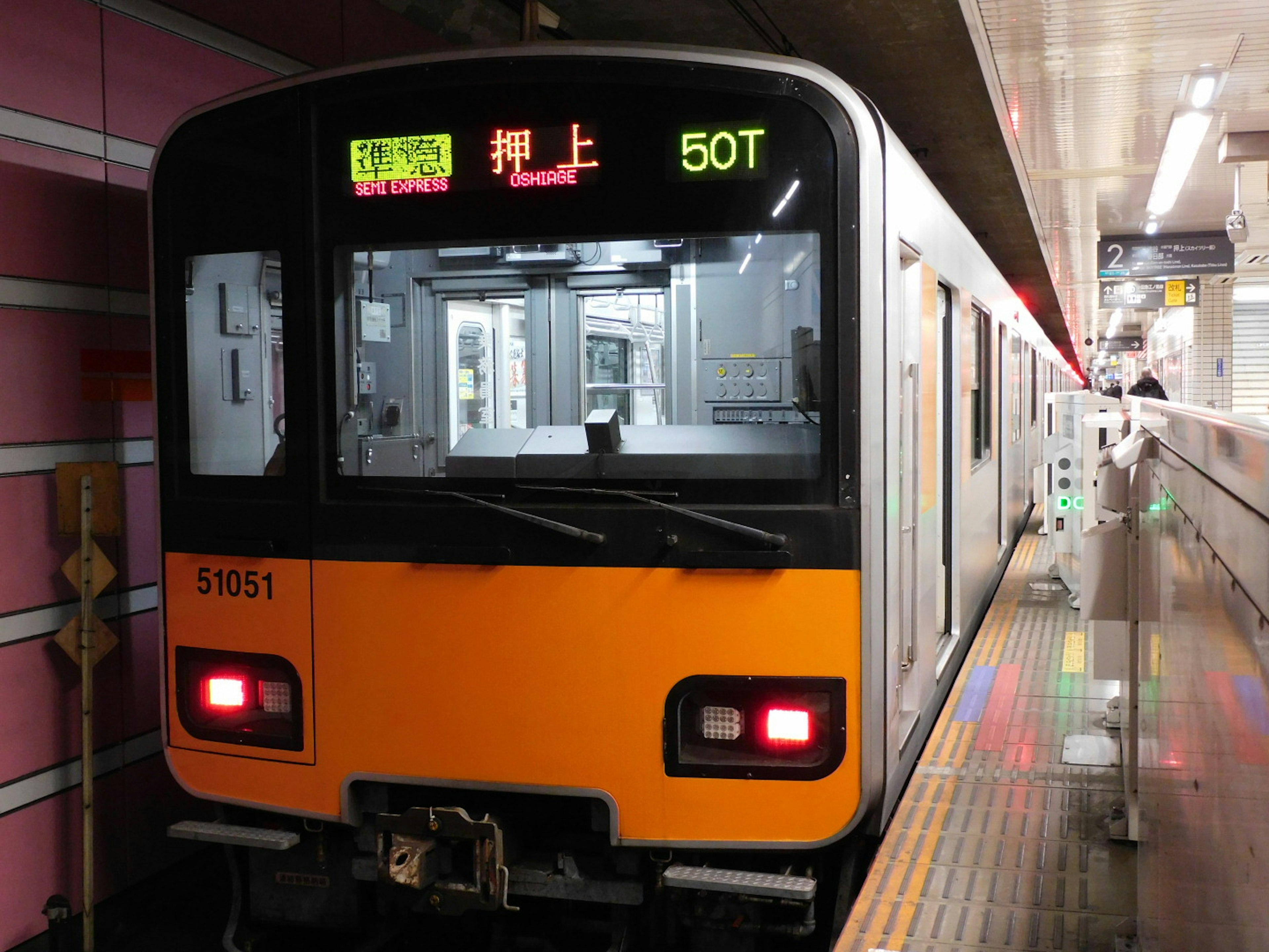 Orange train at a station with operational information displayed on the front