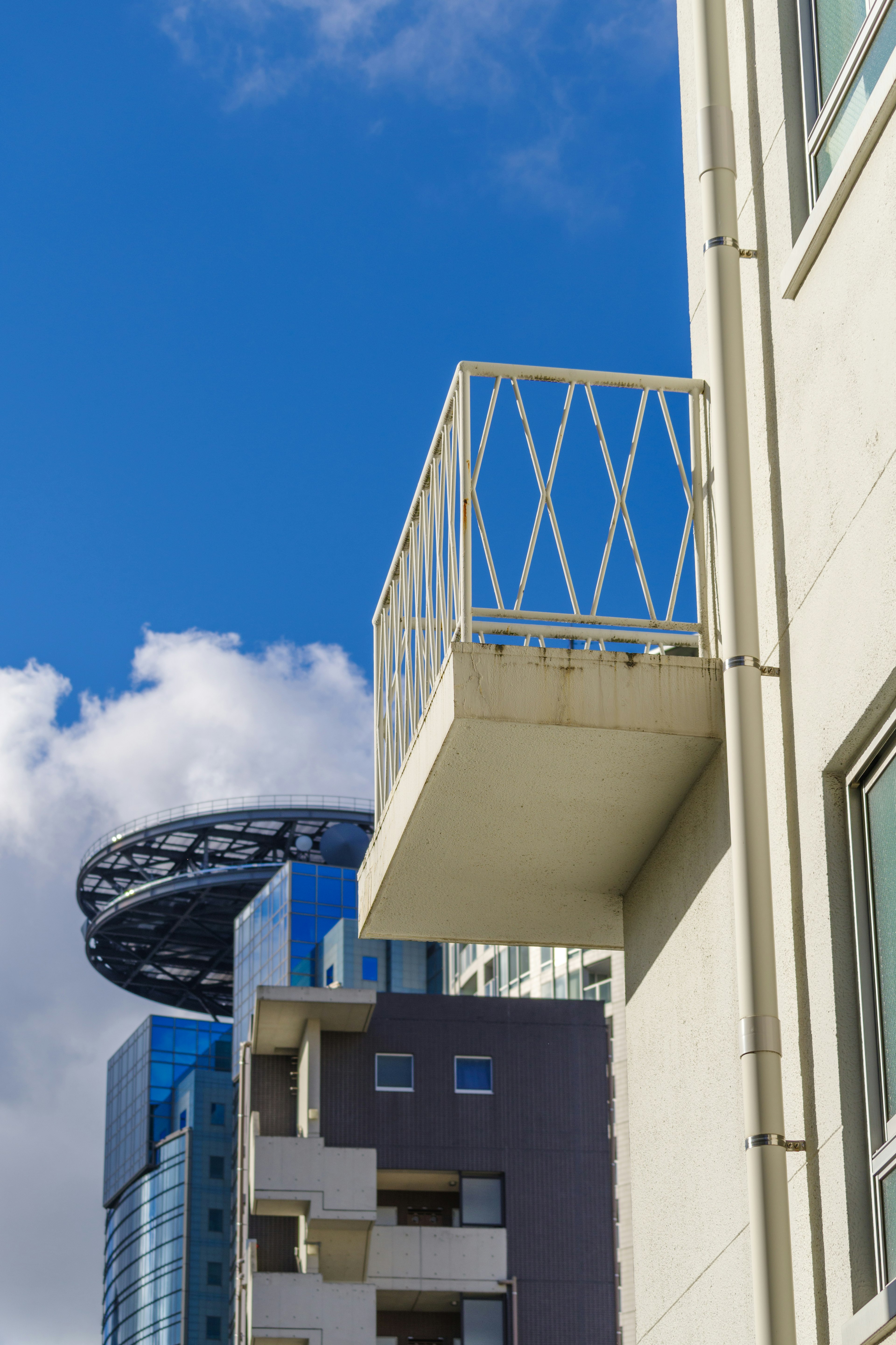 Balcon blanc sous un ciel bleu avec des bâtiments modernes