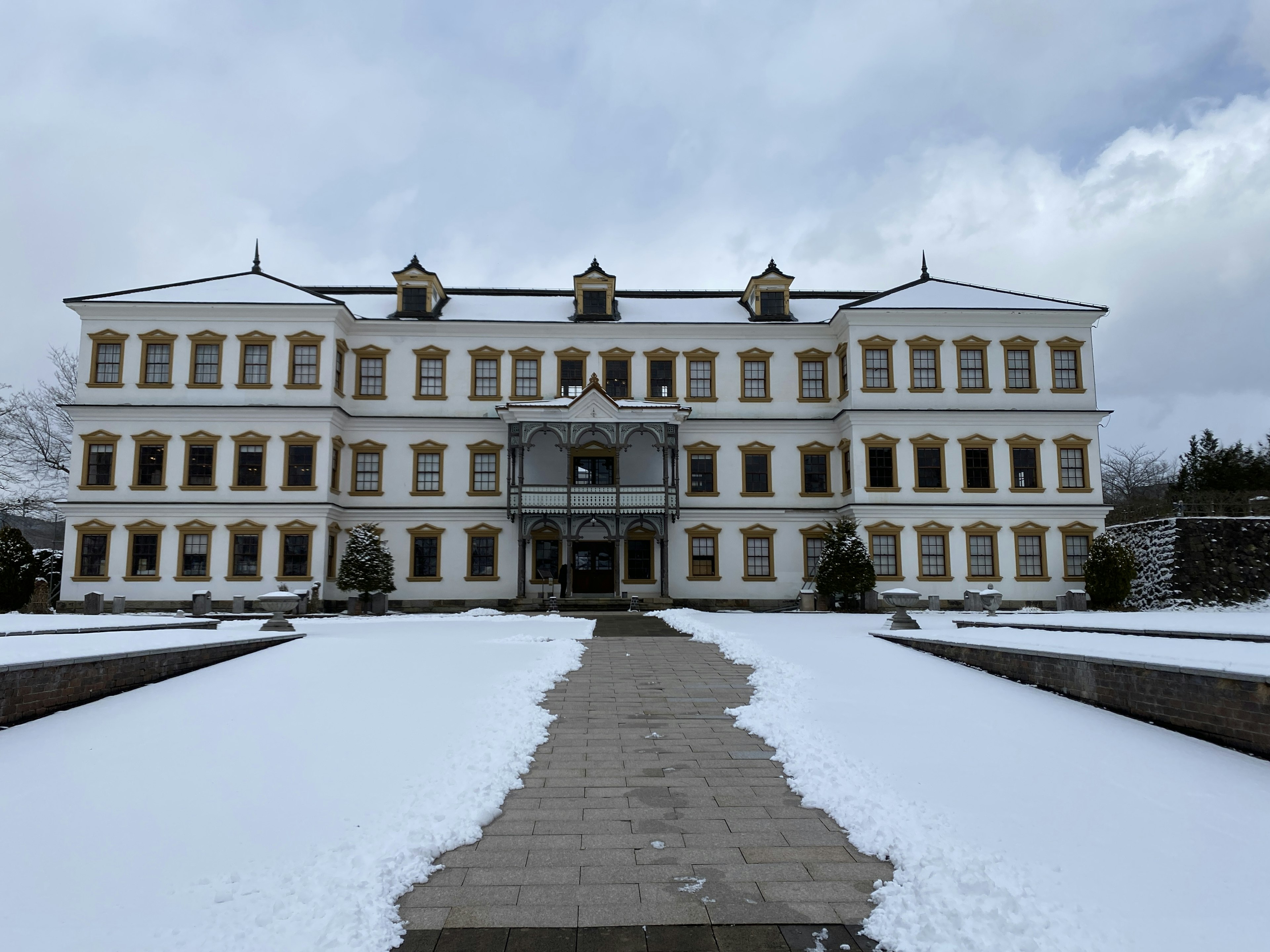 Edificio histórico cubierto de nieve con un camino que lleva a la entrada