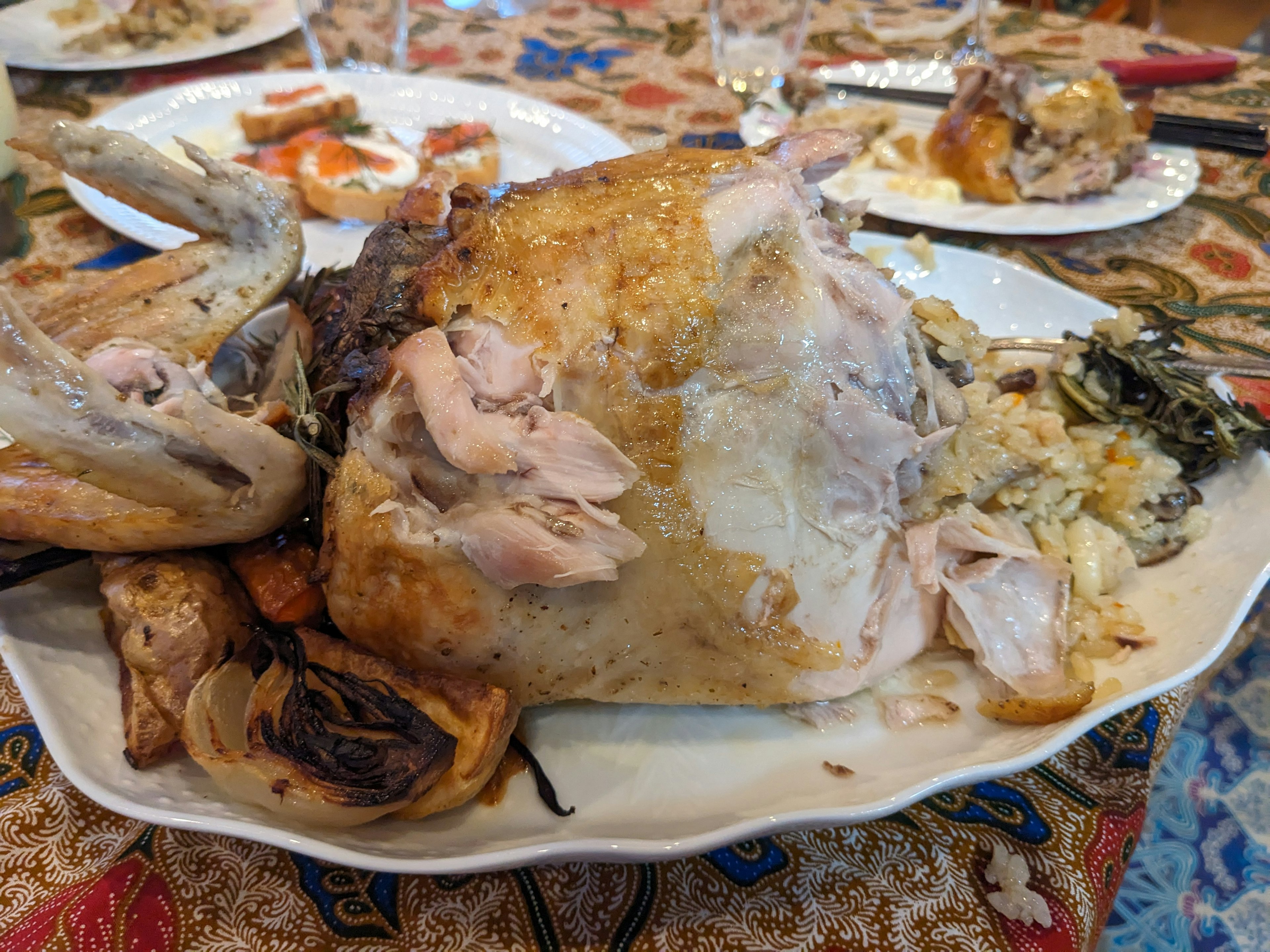 Plate of carved chicken on a dining table with various dishes