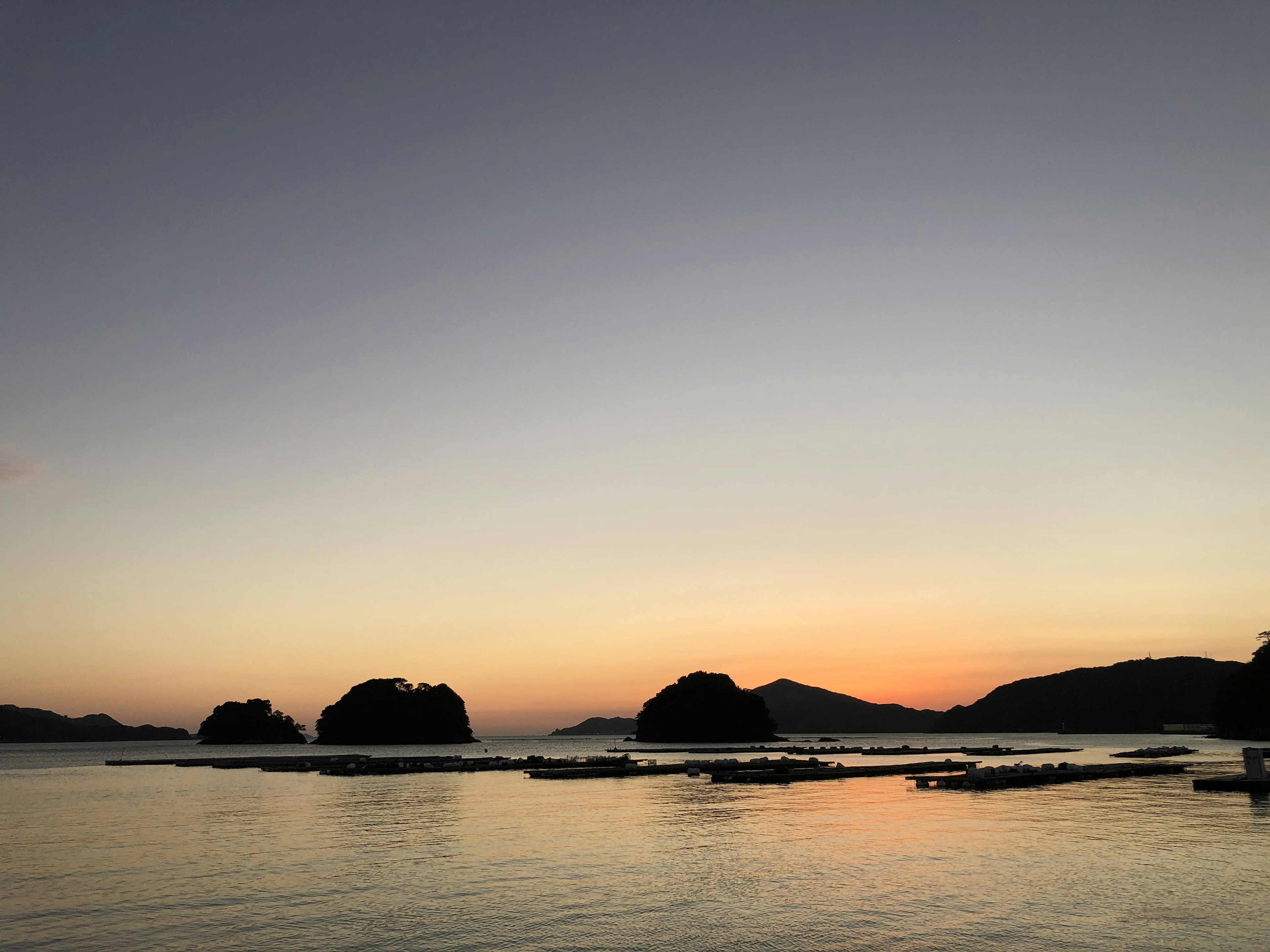 Vue panoramique d'un coucher de soleil sur des eaux calmes avec des îles au loin