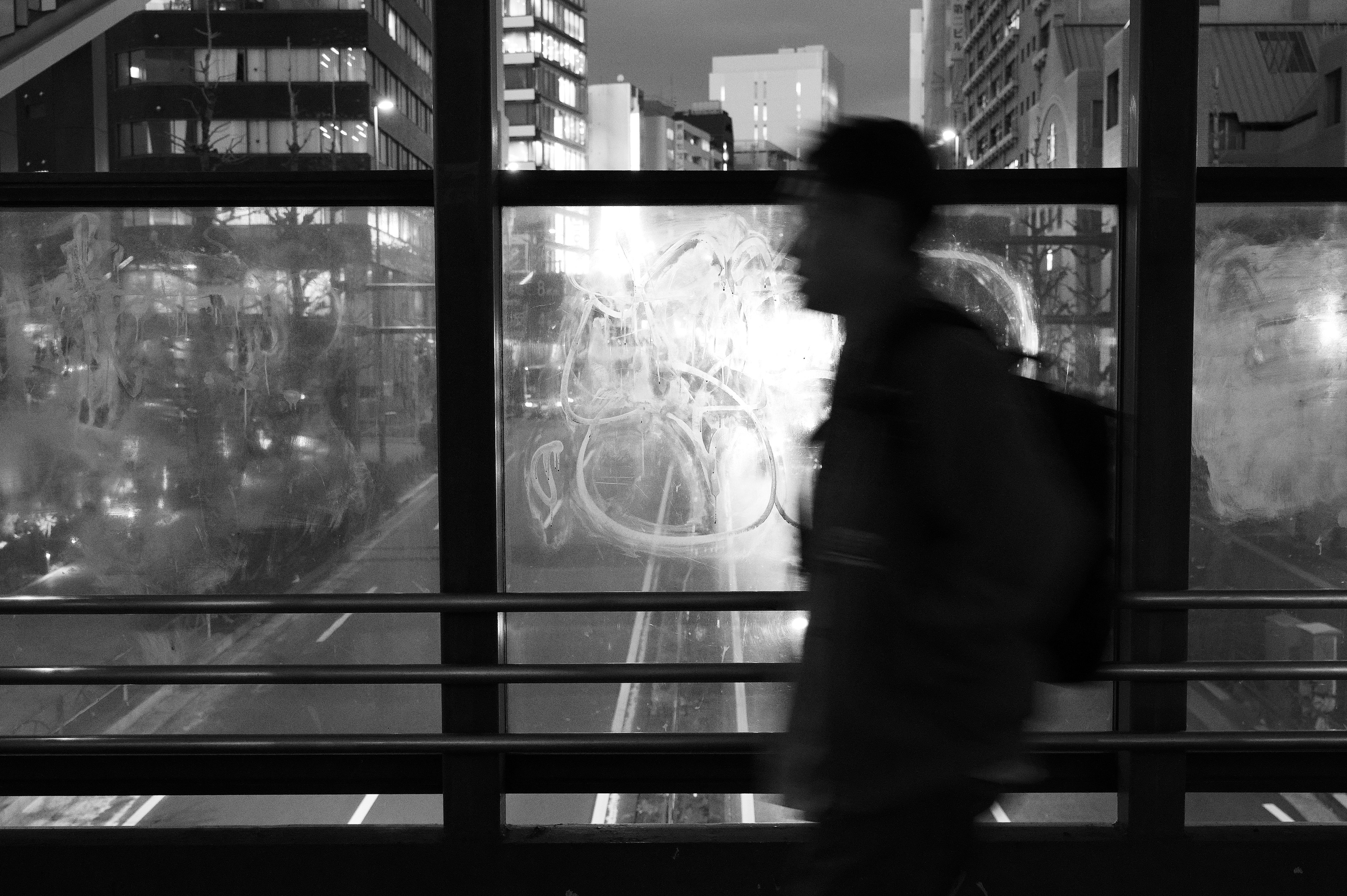 Silhouette of a person against a monochrome cityscape featuring buildings and fogged glass