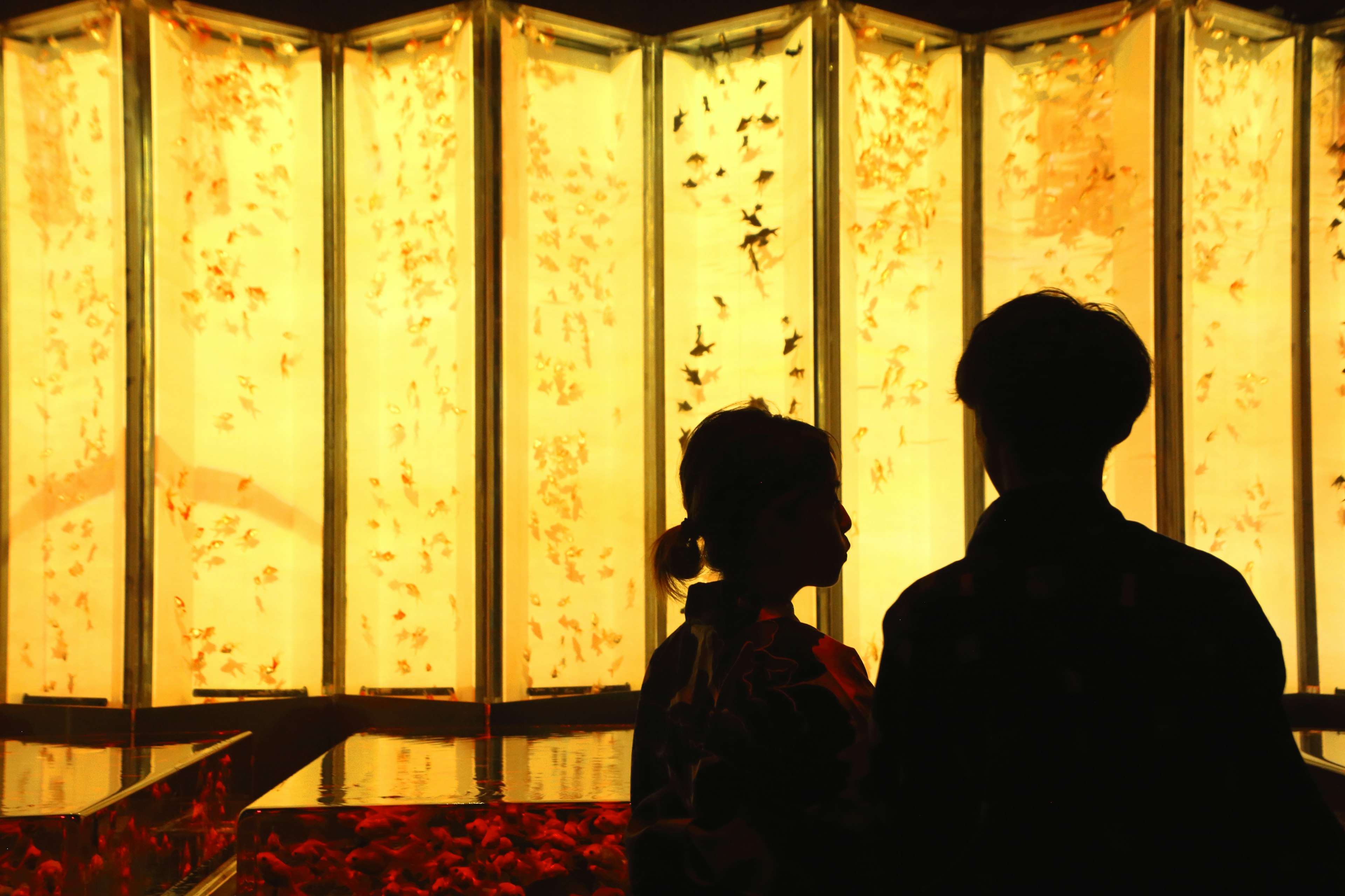 Couple en silhouette contre un fond doré avec des éléments floraux