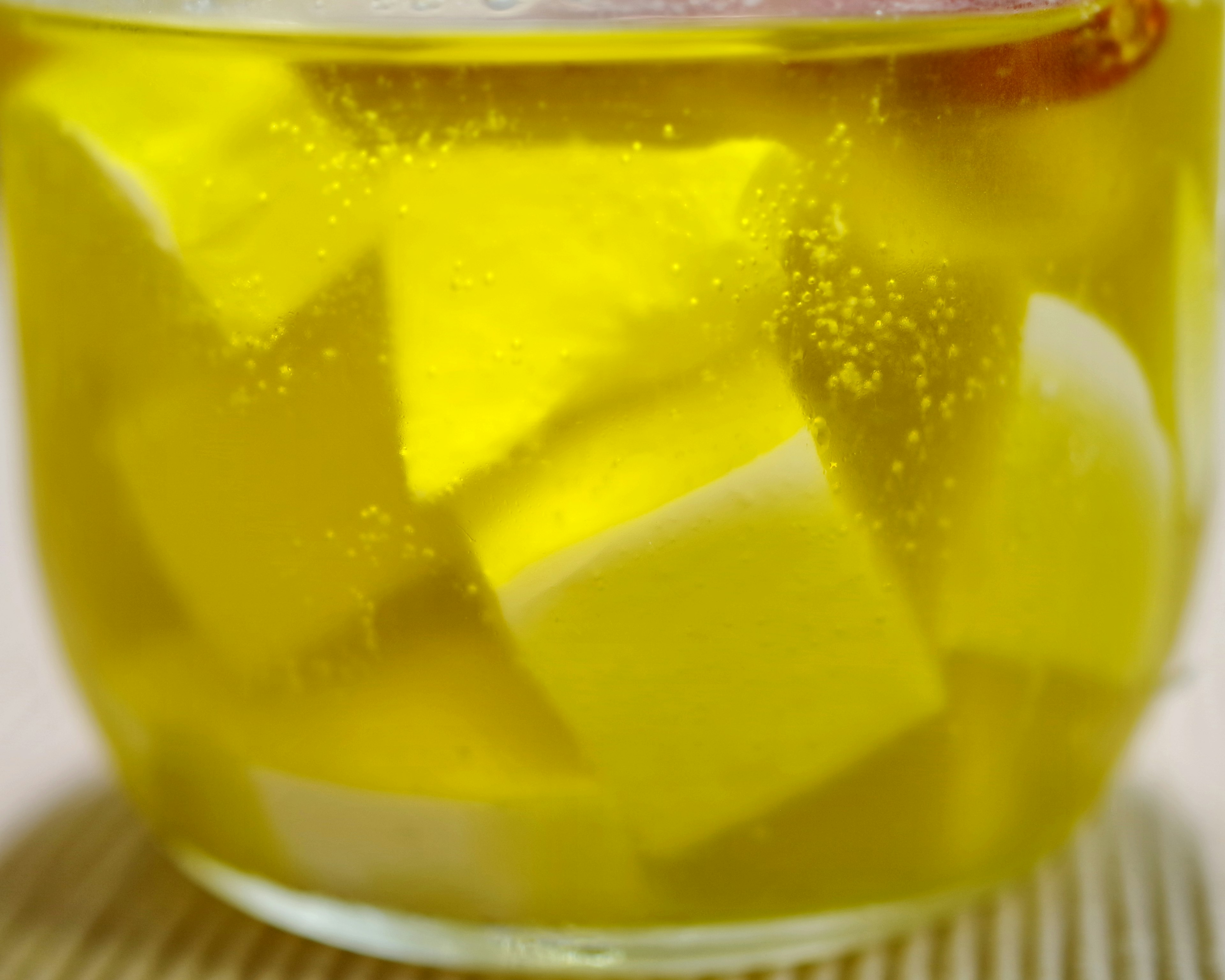 Récipient en verre avec un liquide jaune et des objets en forme de cubes blancs immergés avec des bulles