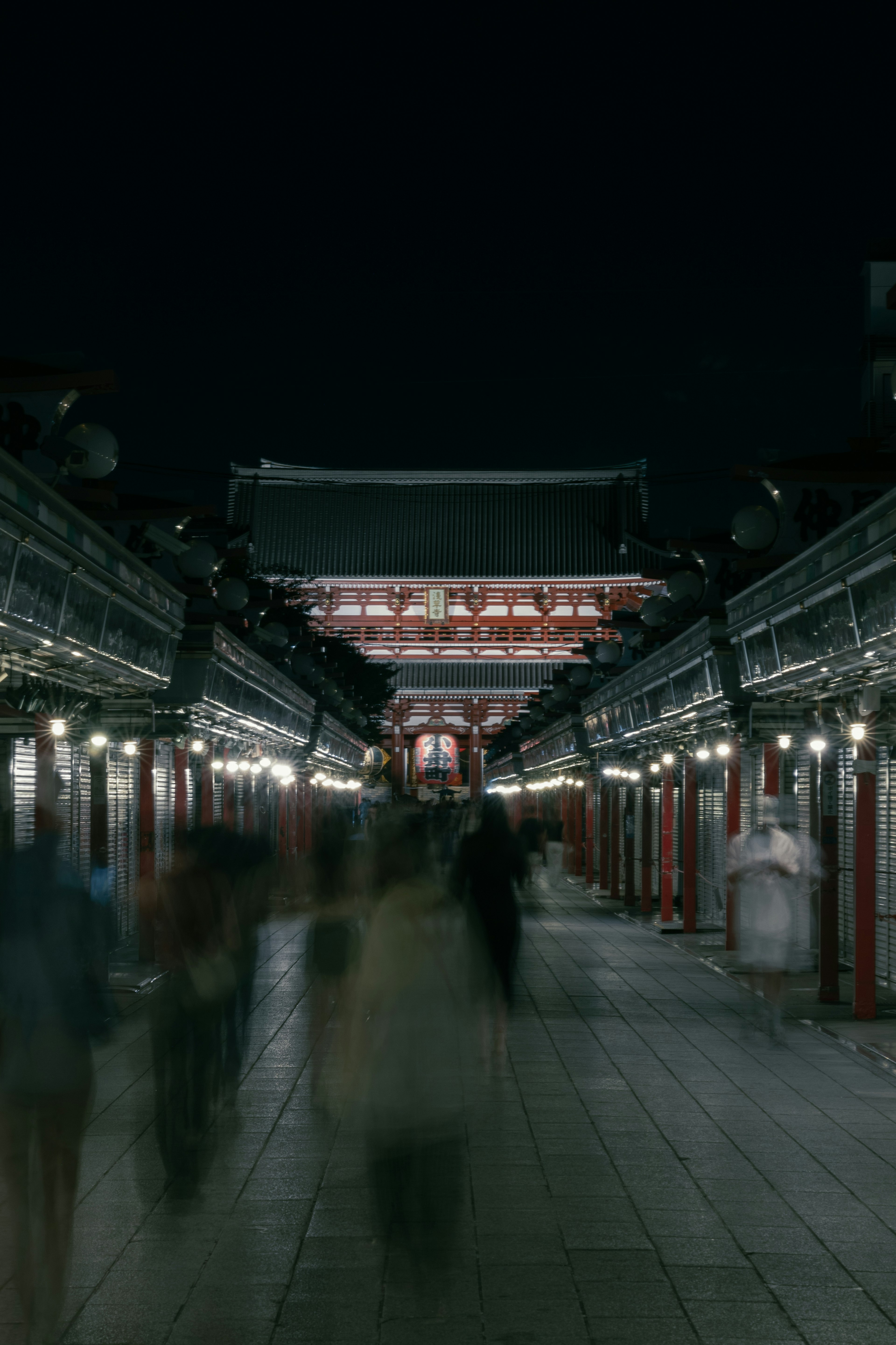 夜の神社の通りに人々が歩いている風景