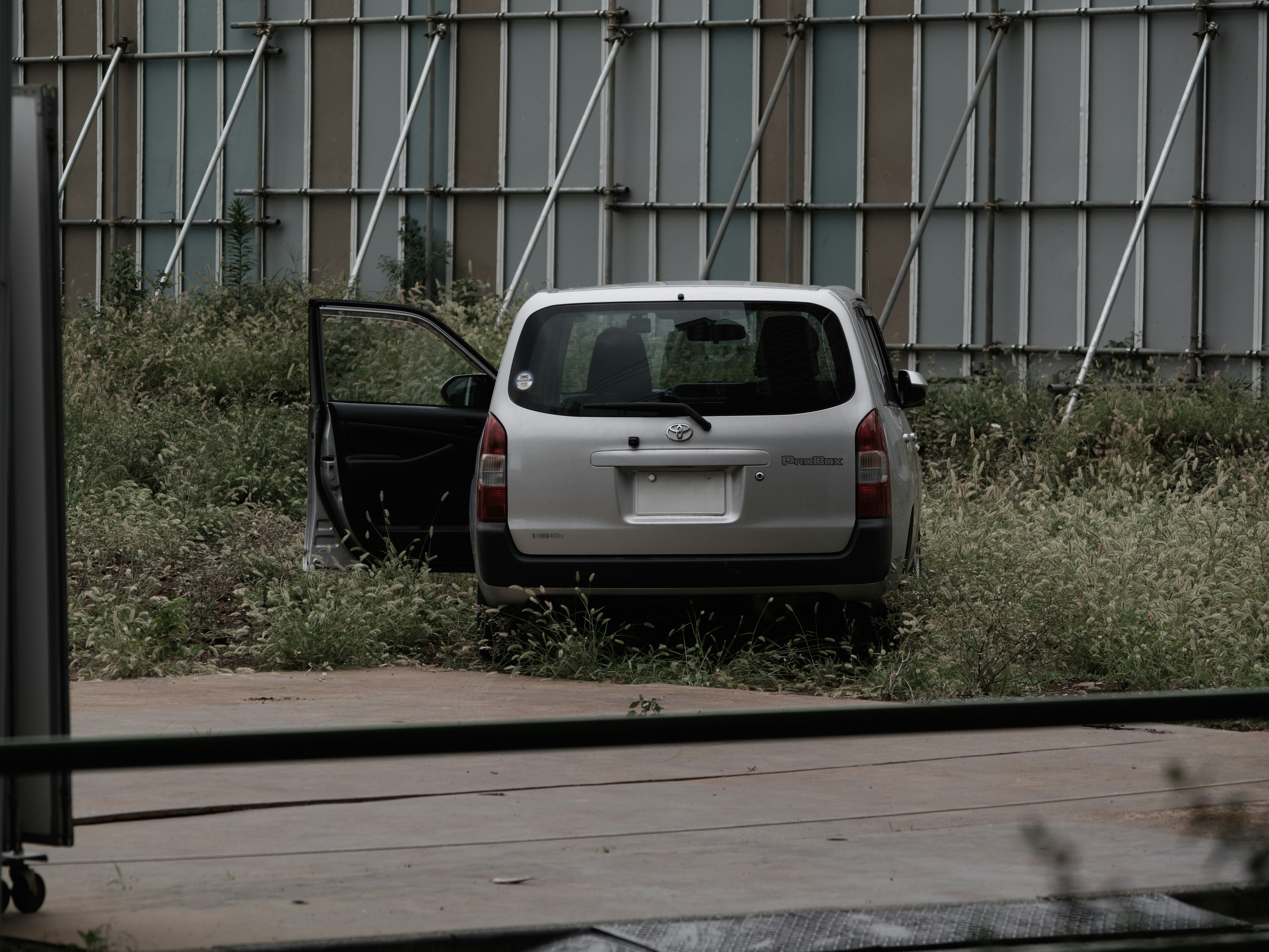 Abandoned silver car with an open door in a grassy area