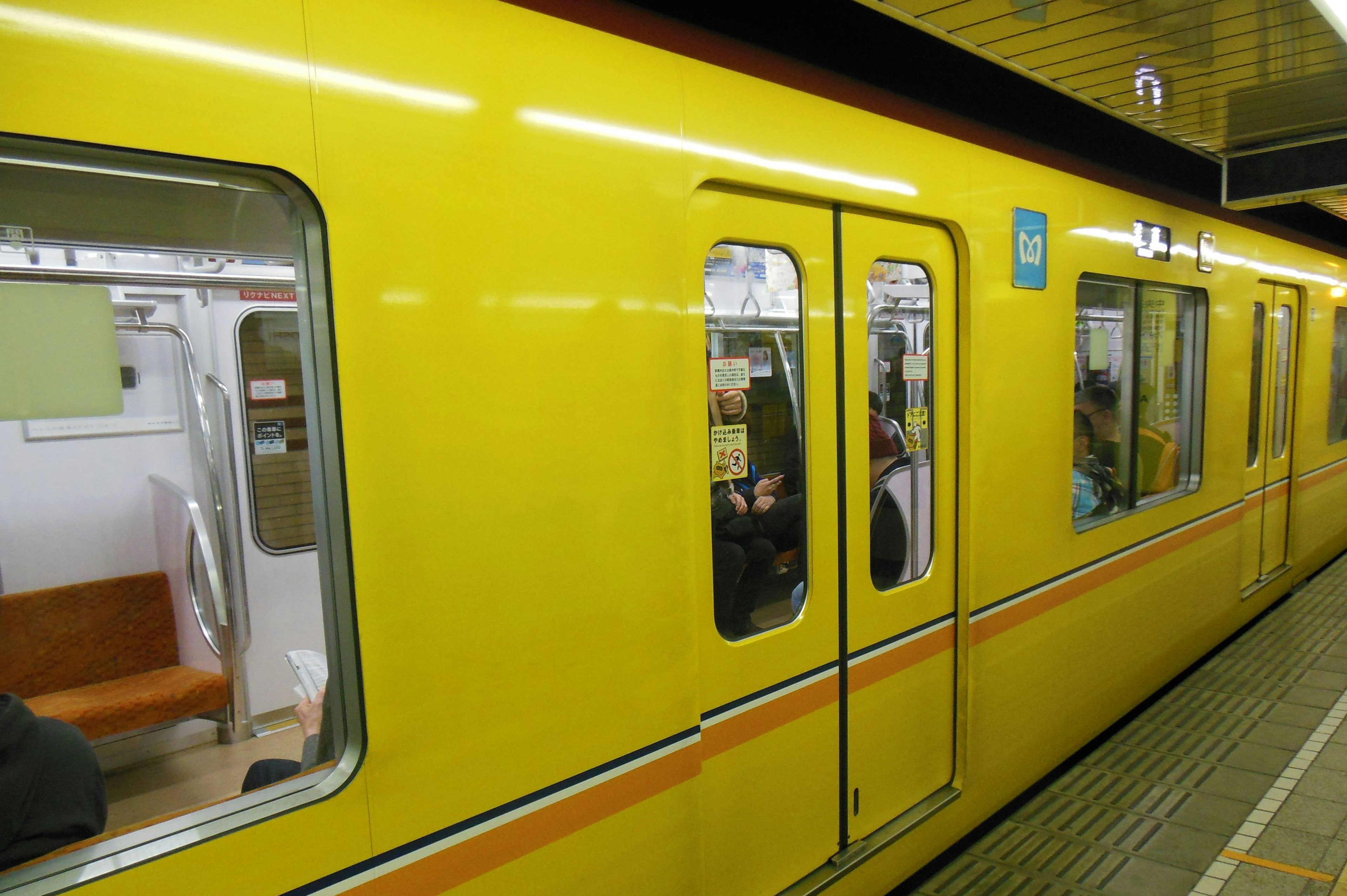 黄色い電車のドアが開いている駅の風景