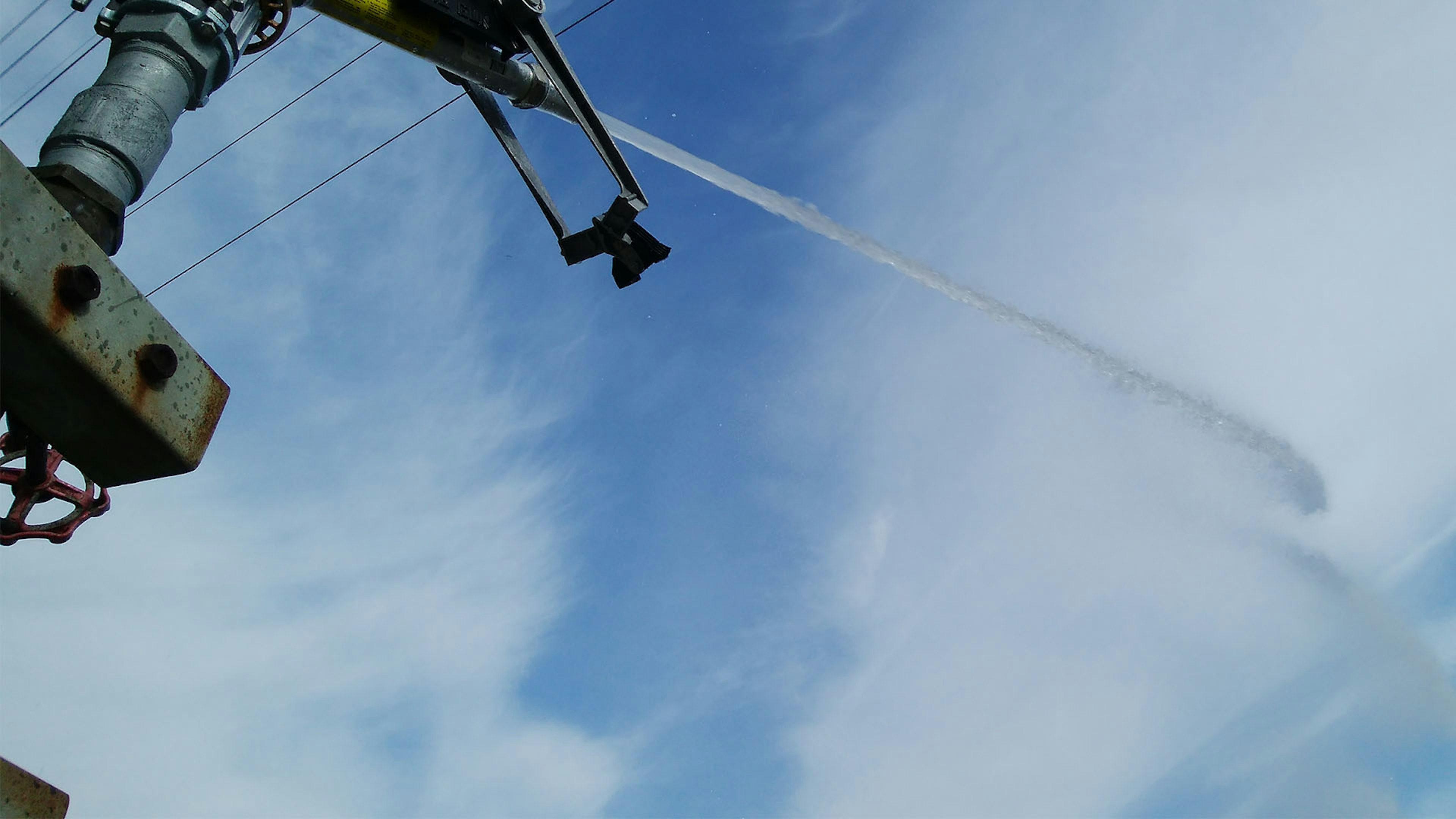 Sebuah perangkat menyemprotkan air ke langit biru dari sudut tinggi