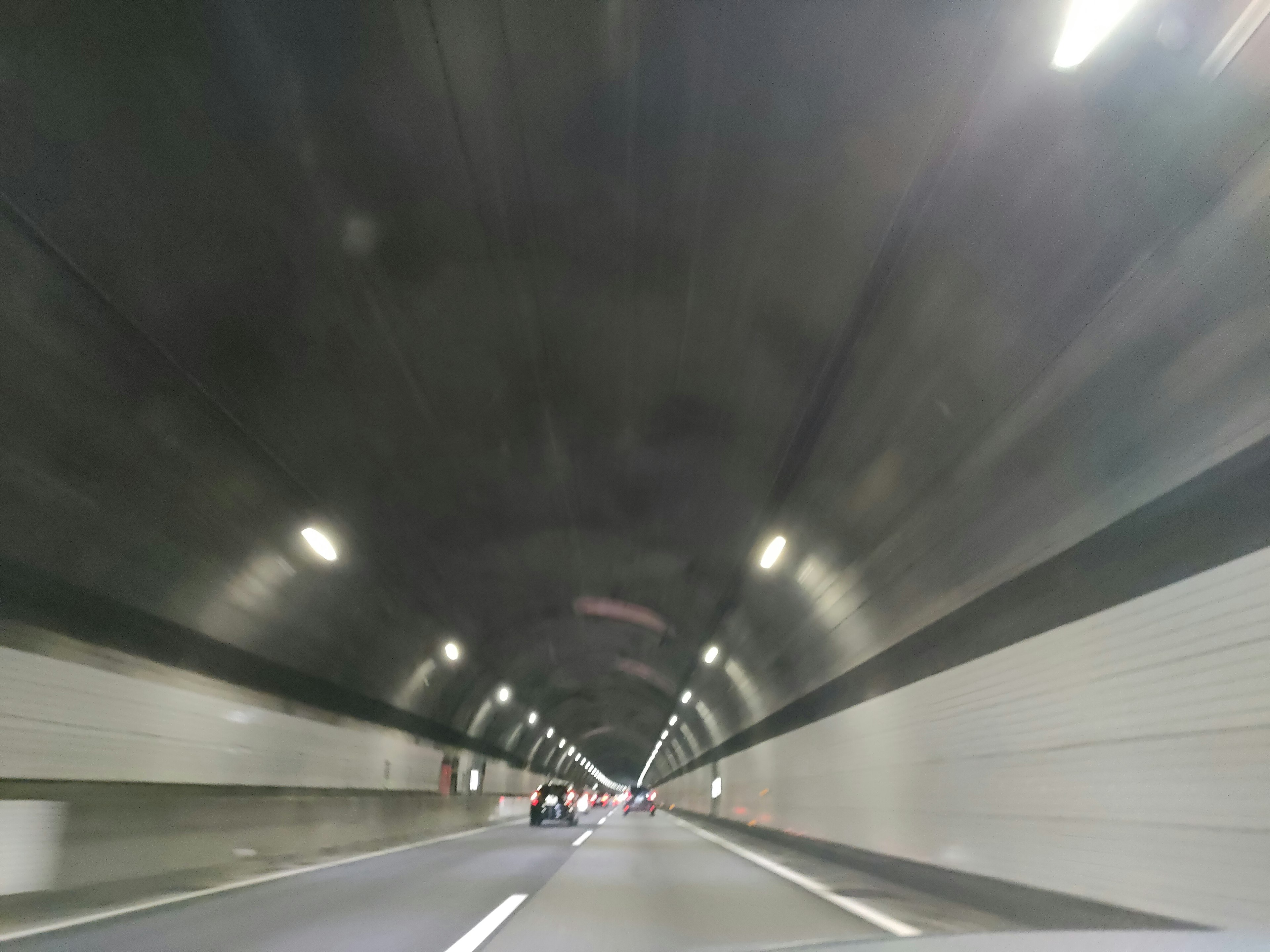 Bild, das eine Perspektive eines Autobahntunnels mit hellen Lichtern und glatten Wänden zeigt