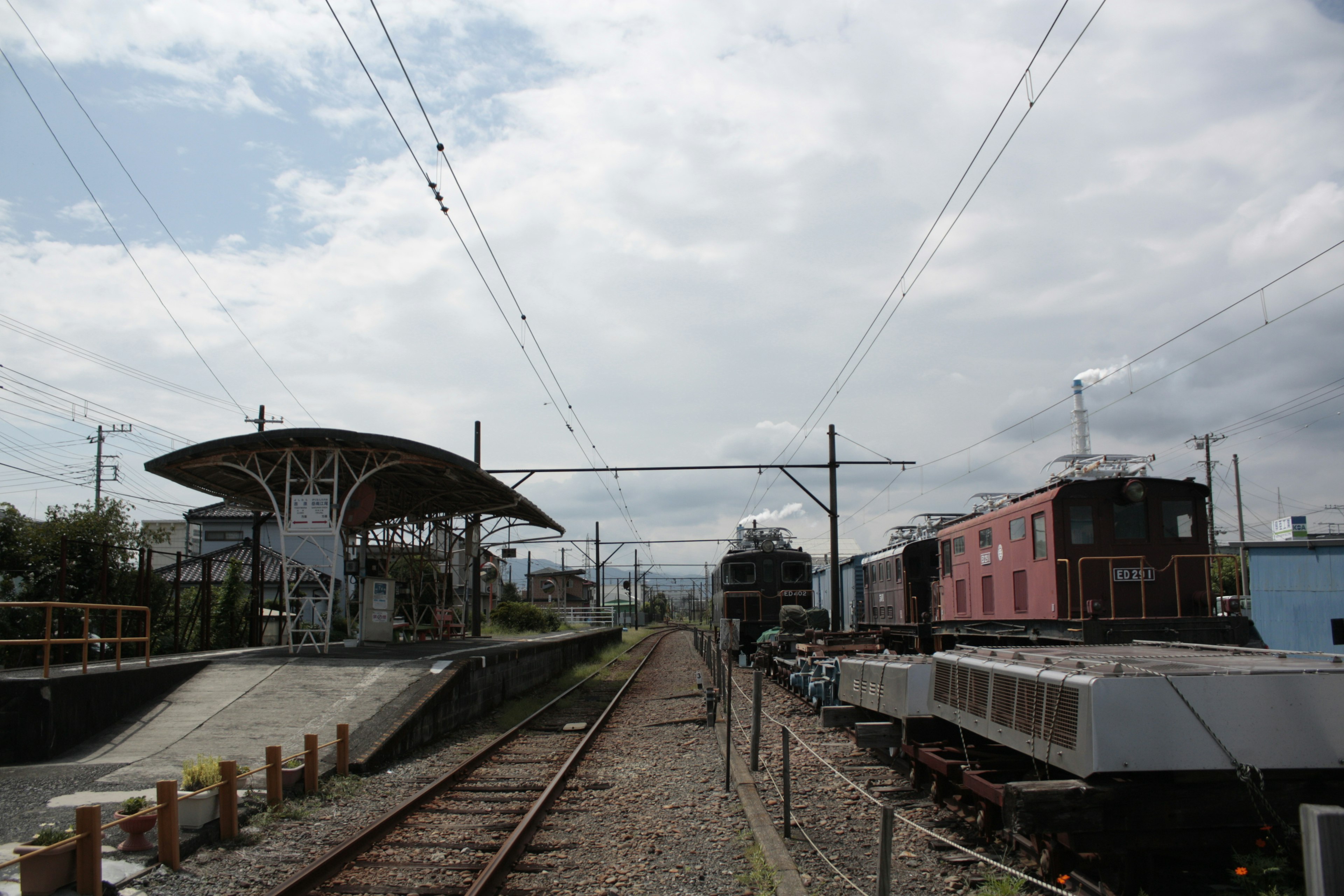 Vista di binari ferroviari con una stazione e treni d'epoca