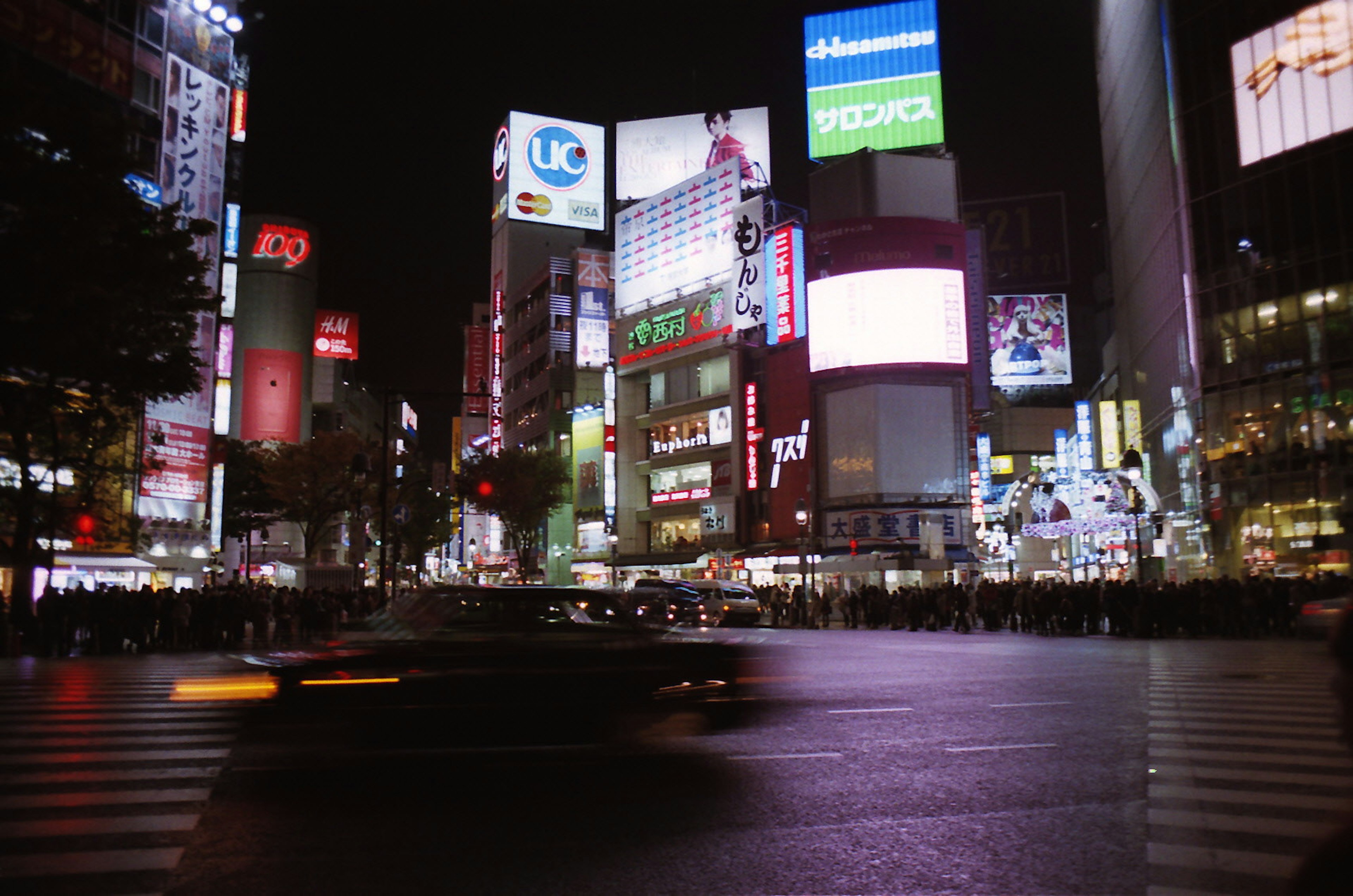 Shibuya intersection at night Bright neon signs and moving cars