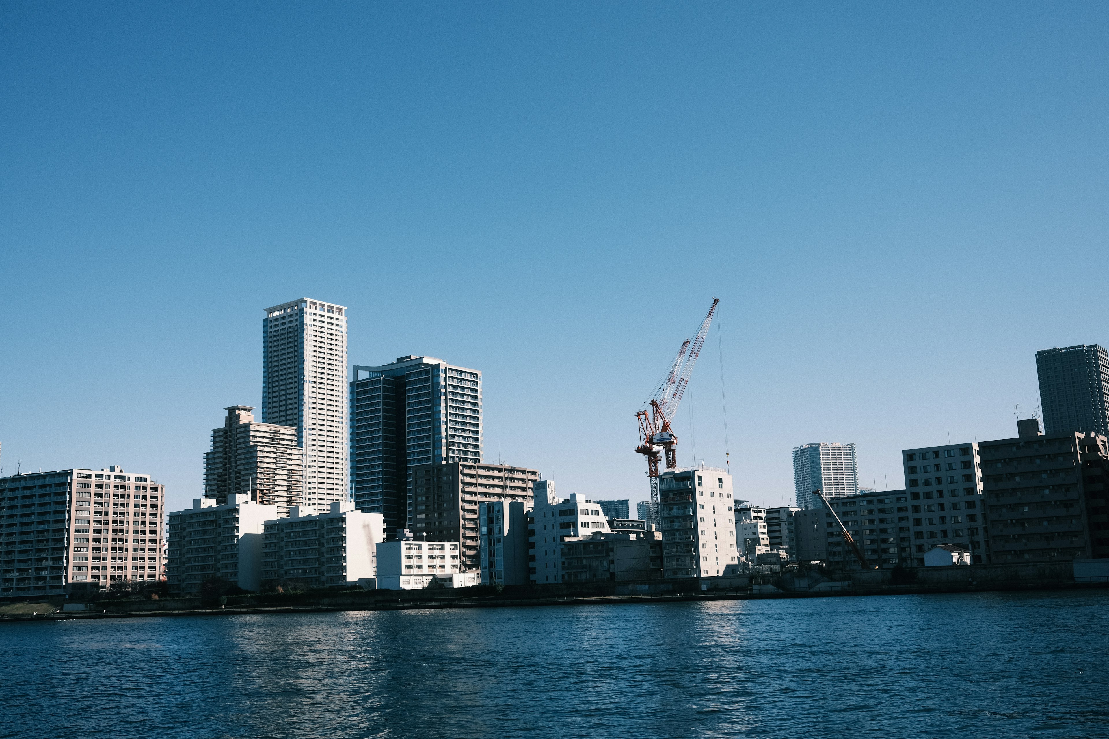 City skyline with high-rise buildings against a clear blue sky and water