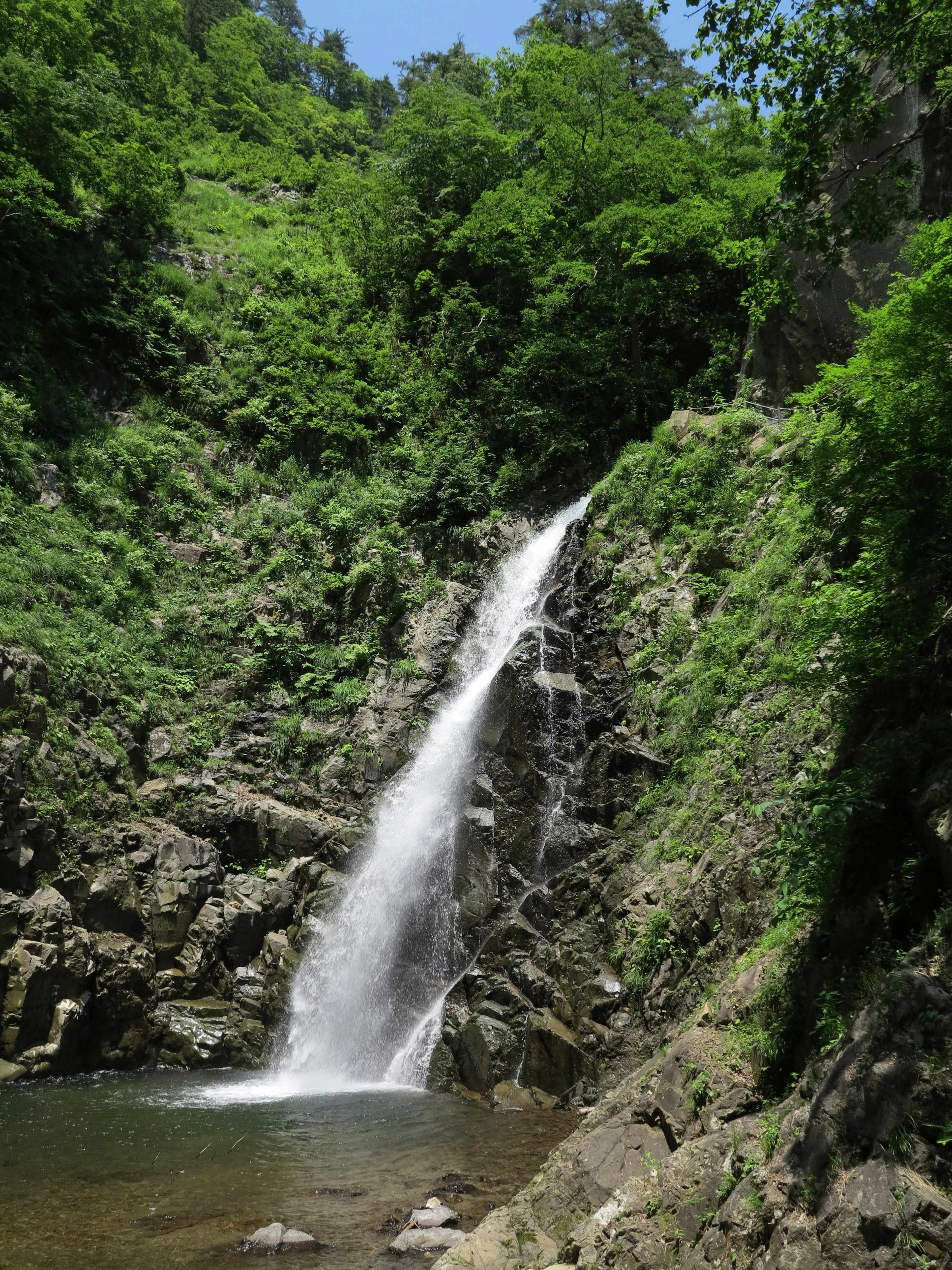 Ein schöner Wasserfall, der zwischen Felsen von grünem Bewuchs umgeben fließt