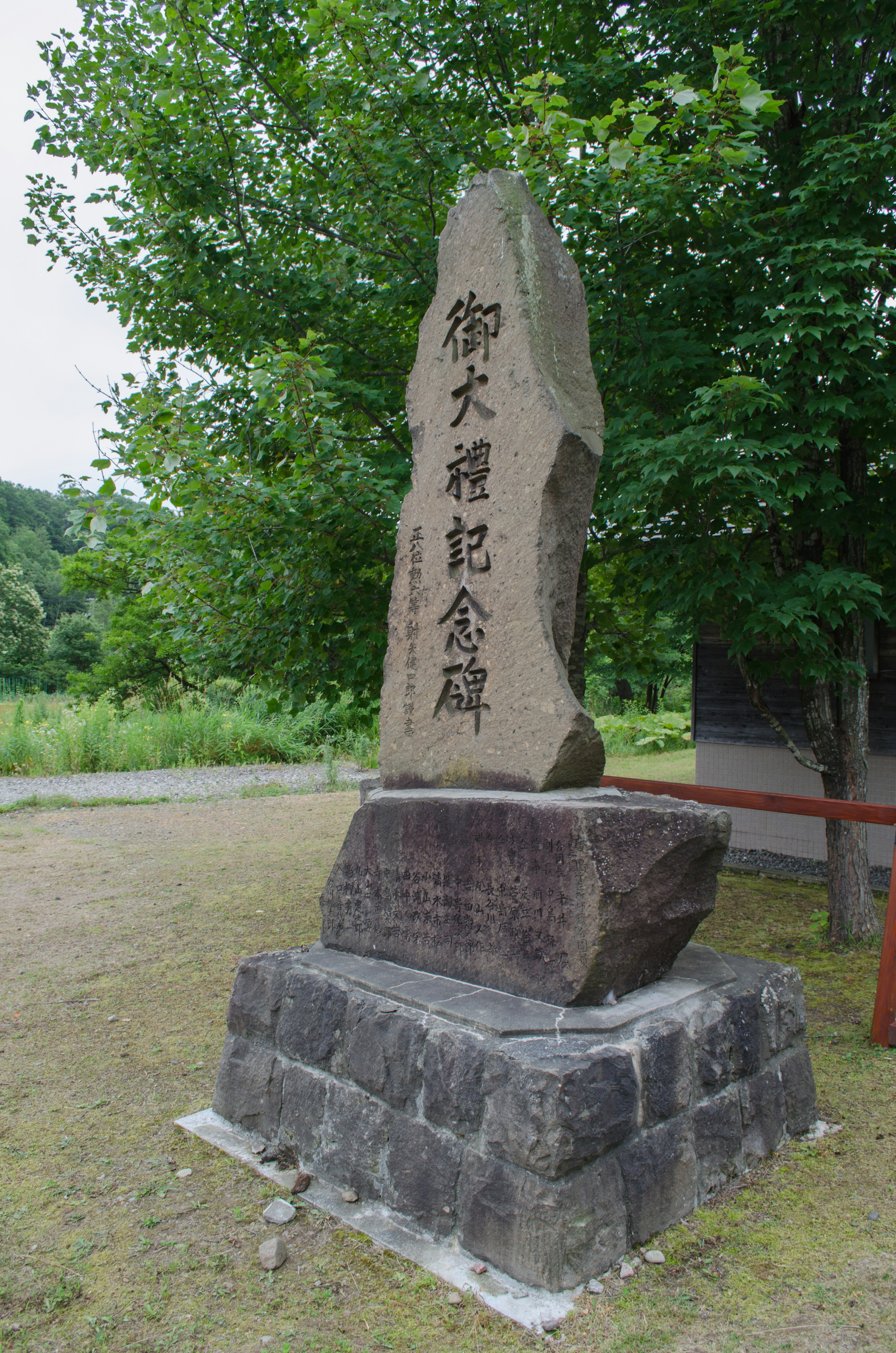 A stone monument standing among green trees