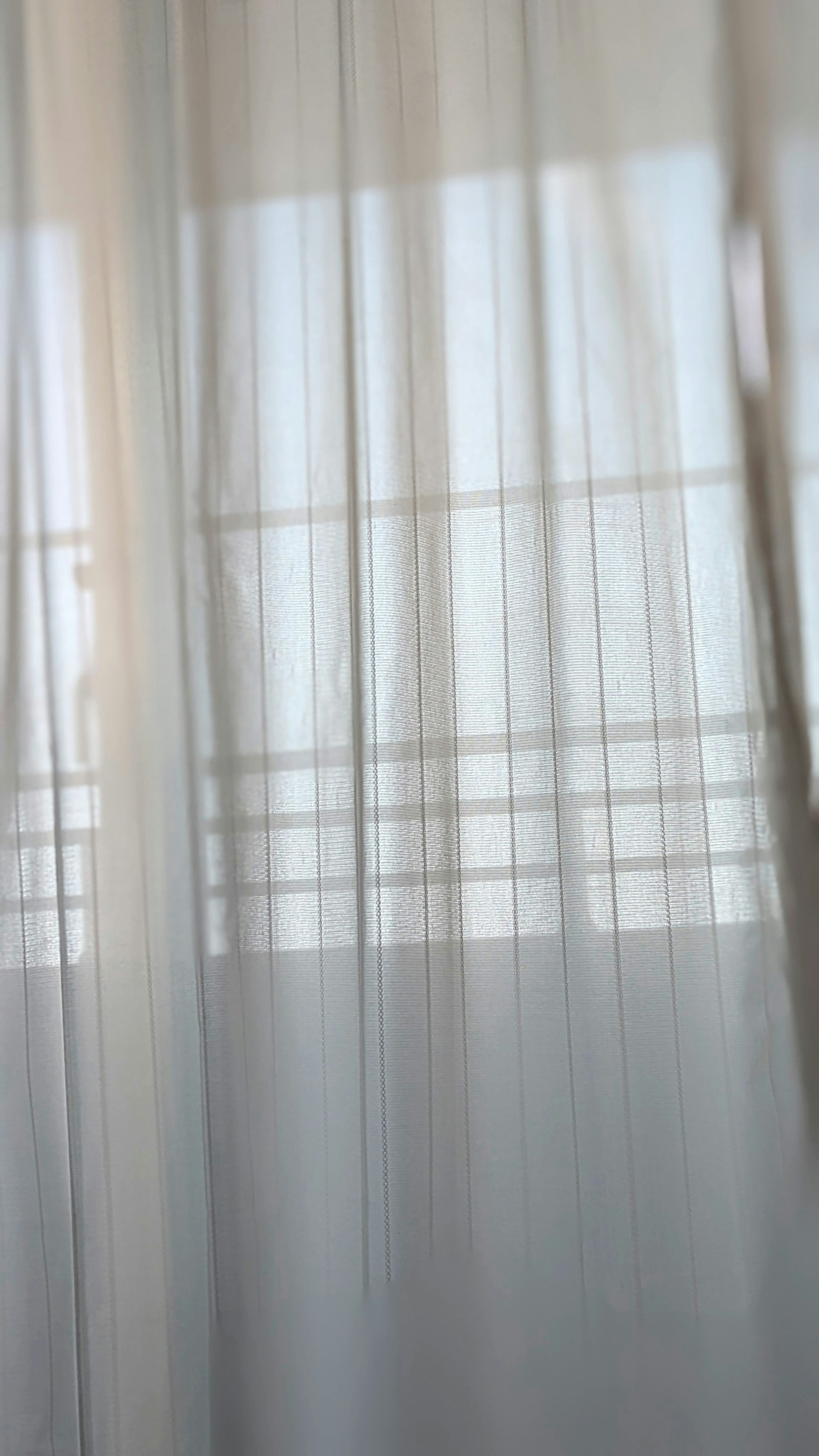 Sheer curtains revealing a window and balcony view