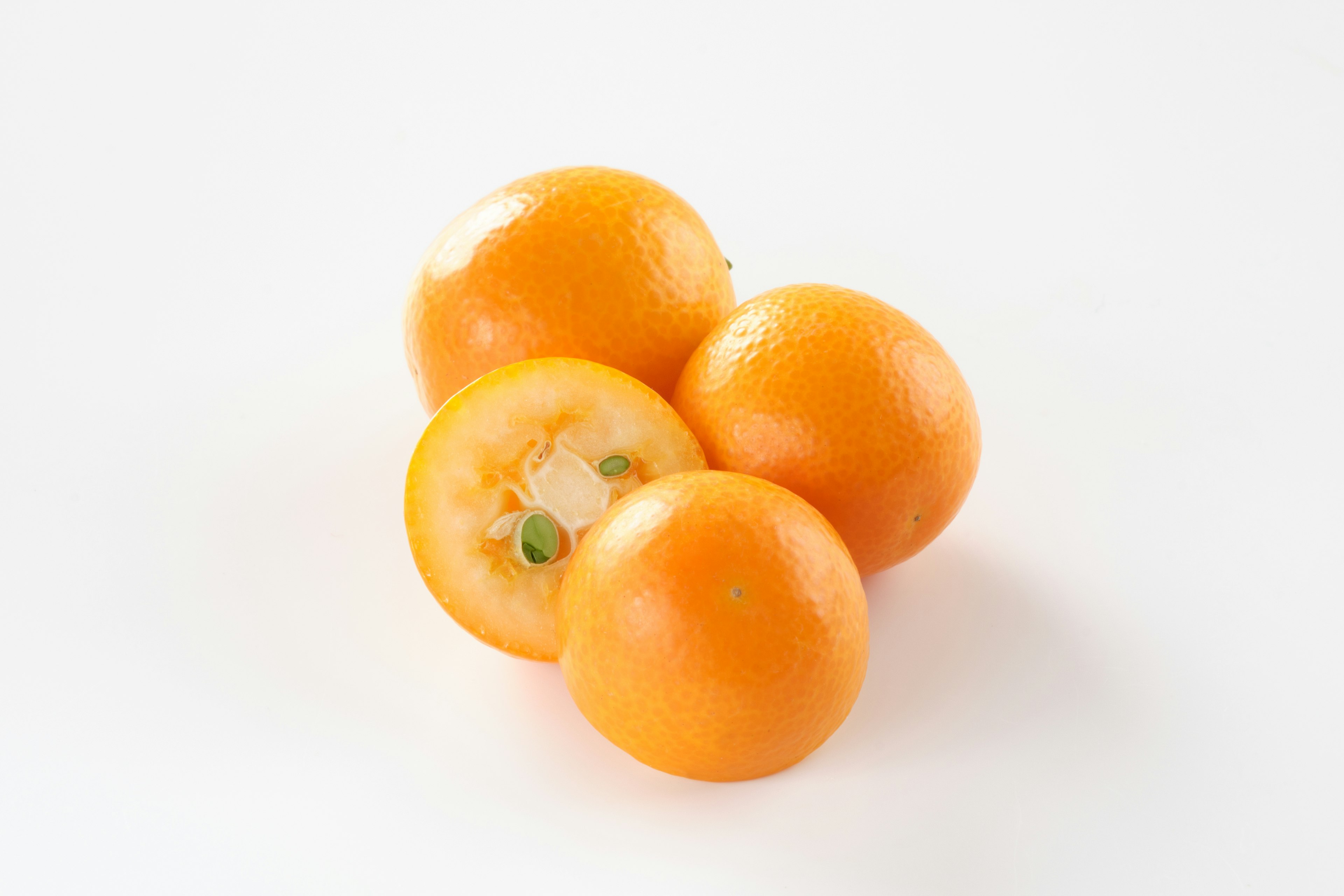 Three oranges on a white background with one cut in half