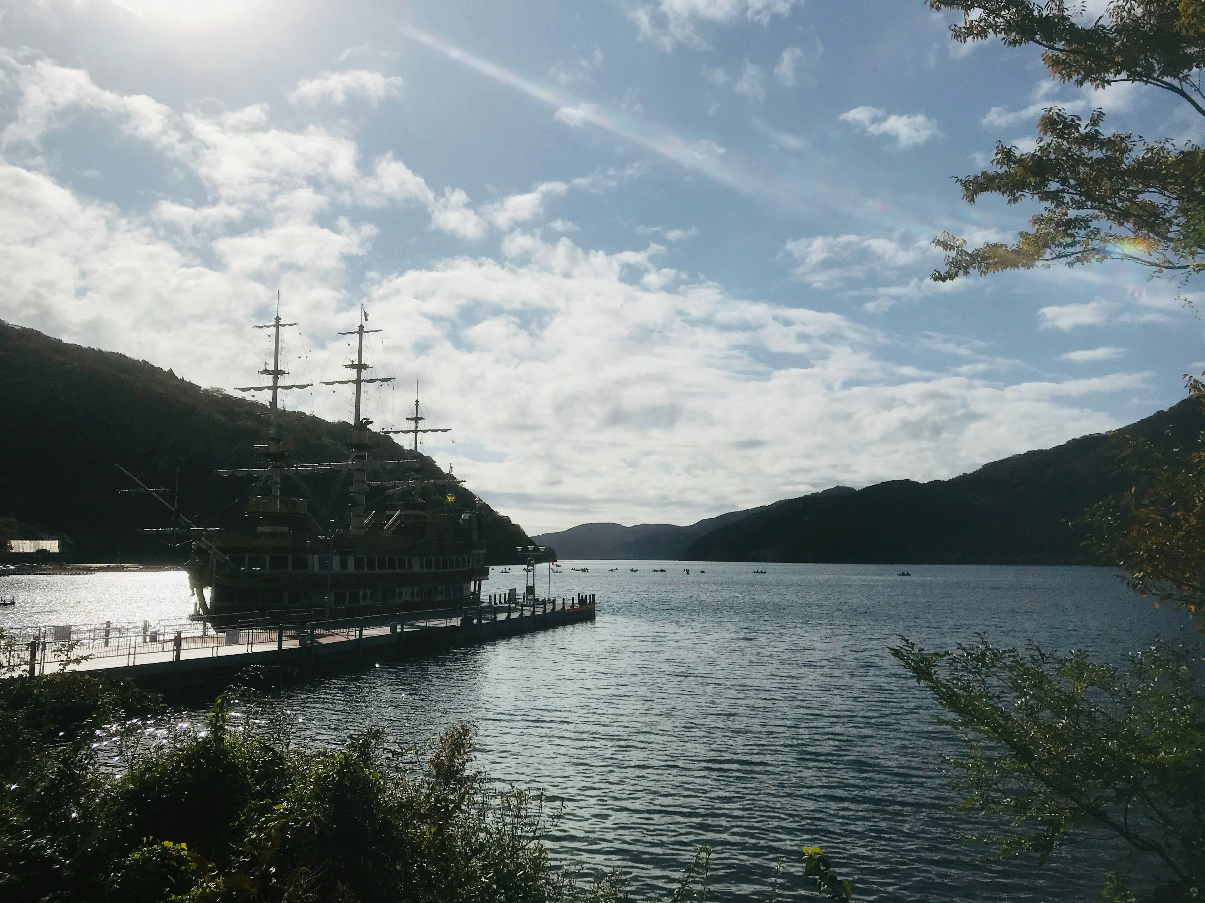 A docked sailing ship surrounded by mountains and water