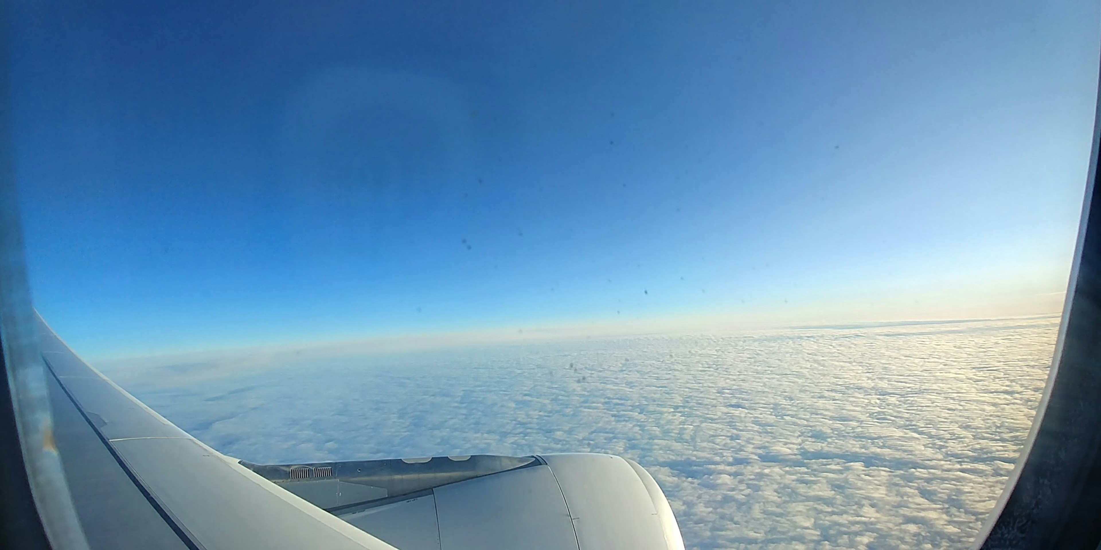 Pemandangan awan dan langit biru dari jendela pesawat