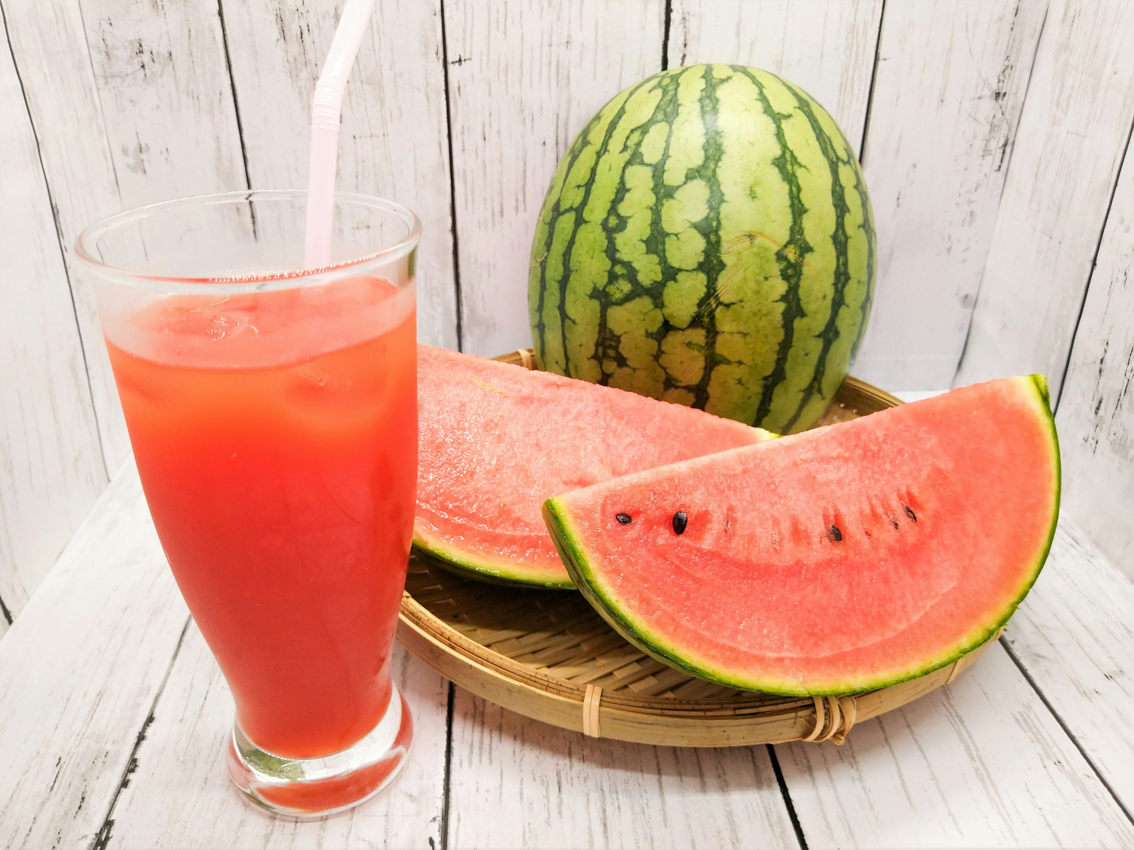 Bild von Wassermelone und Wassermelonensaft Wassermelonenscheiben auf einem Bambusteller Hintergrund mit weißer Holzstruktur