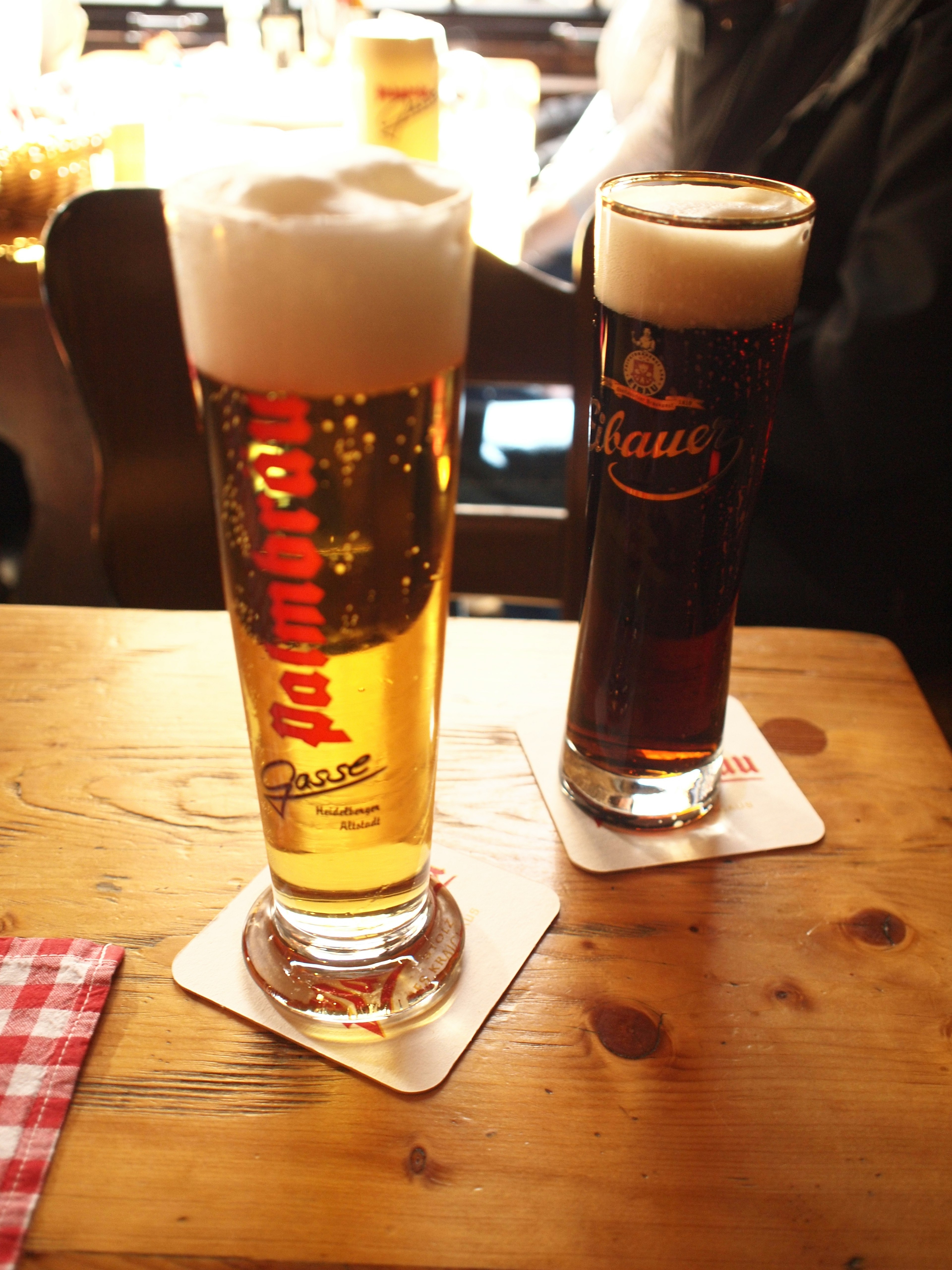 Zwei Biergläser auf einem Holztisch mit einem hellen Bier und einem dunklen Bier