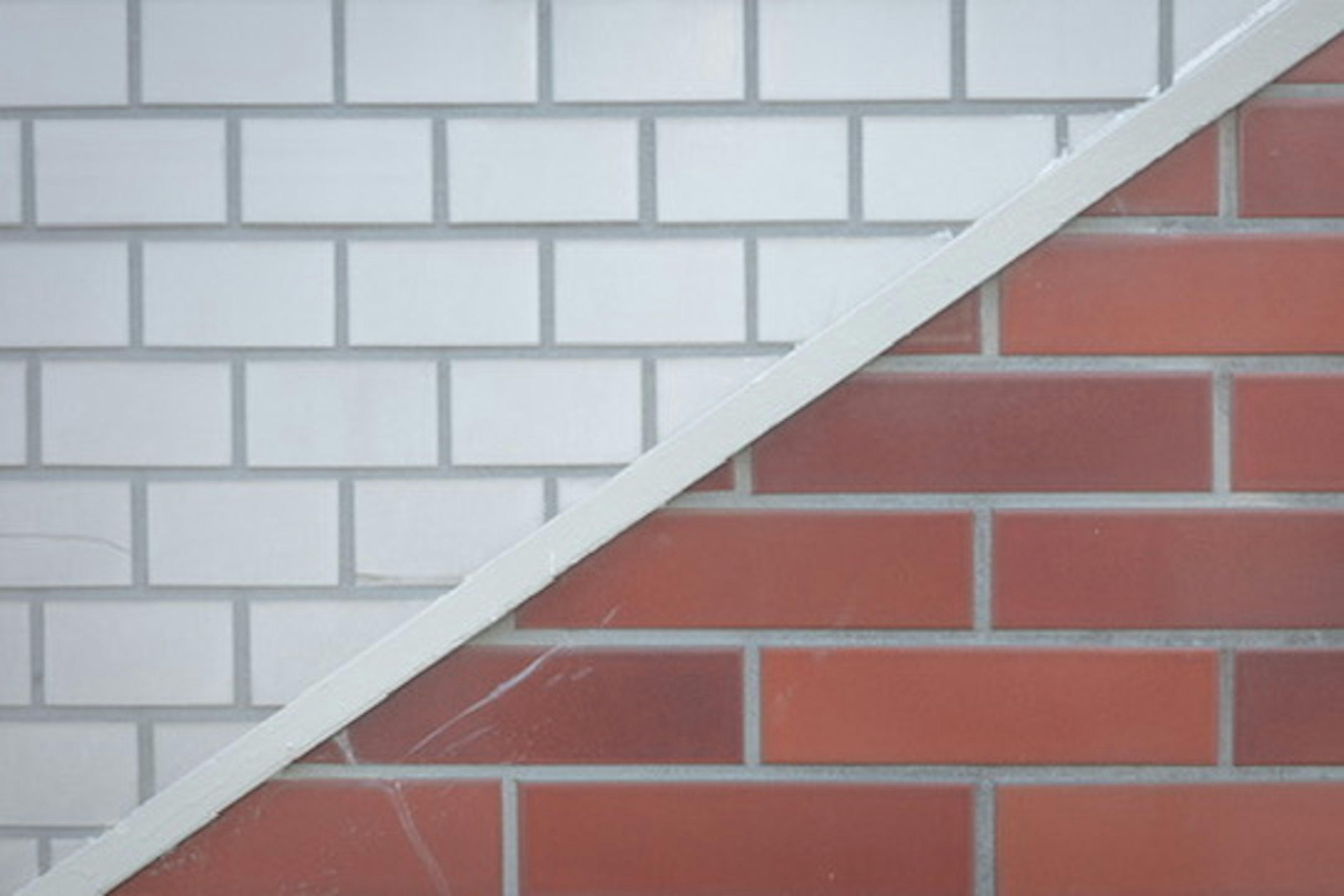 Diagonal split wall featuring white tiles on one side and red tiles on the other